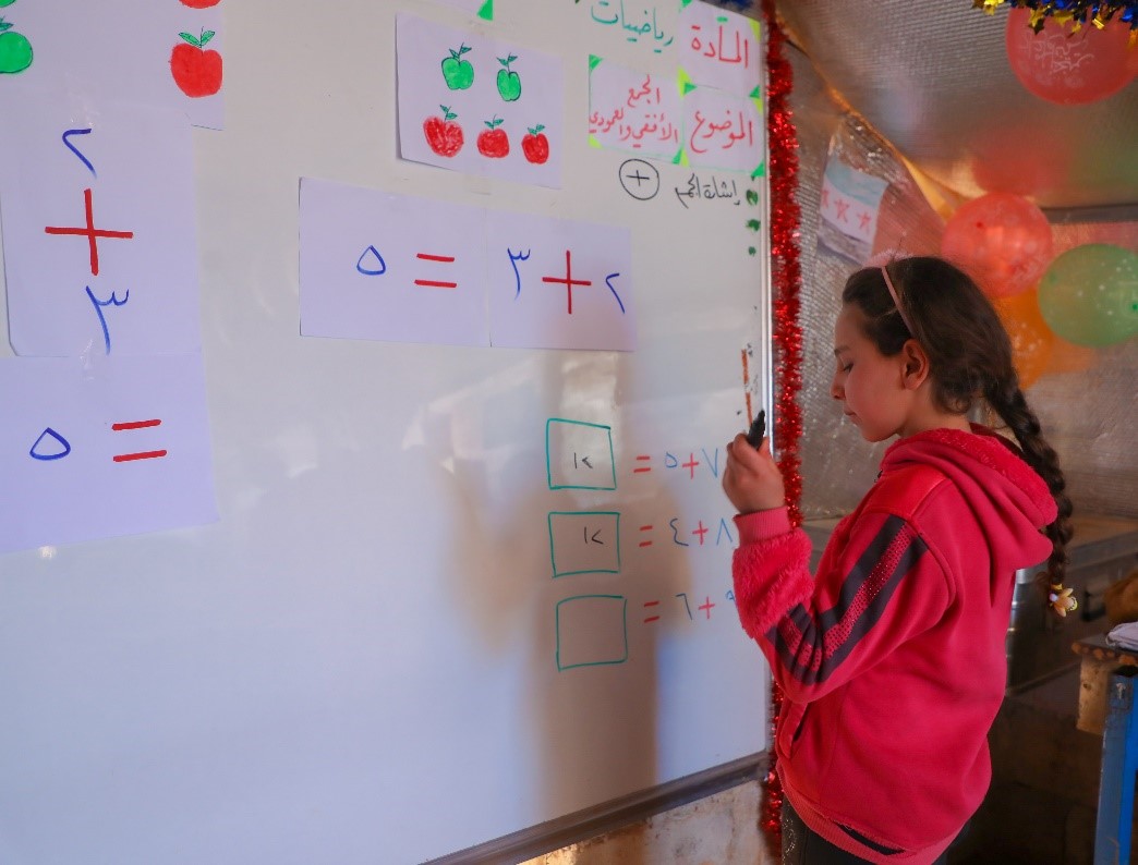 Haneen* calculates numbers and writes the answer on the board. ⒸWorld Vision Syria Response, Zaher Jaber