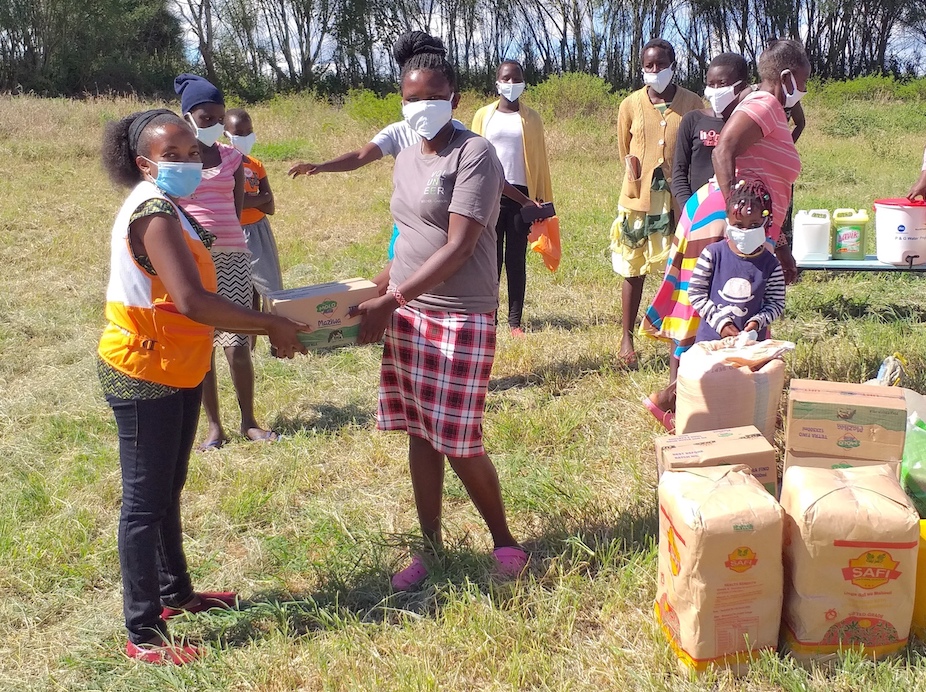 4-Tabitha Mwangi, left donates food items to a teacher at Ilbisil Primary School and Rescue Centre at Osiligi in Kajiado County, Kenya. The food will help cushion the children from the adverse effects of COVID-19.