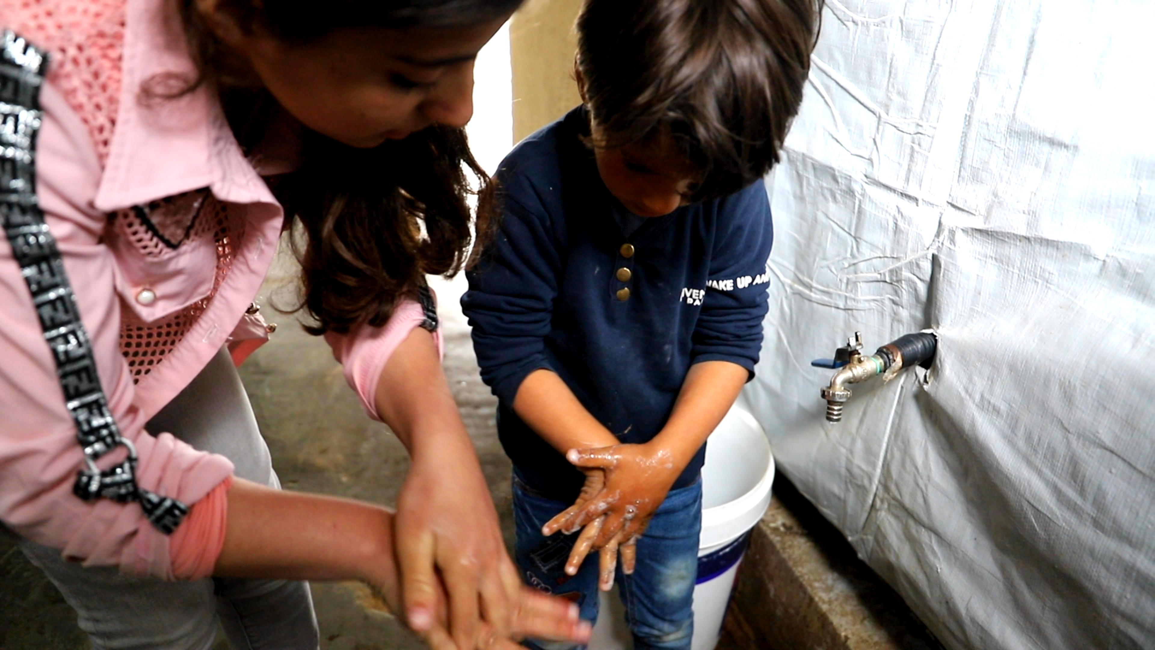 Yasmine teaching her brother how to wash his hands