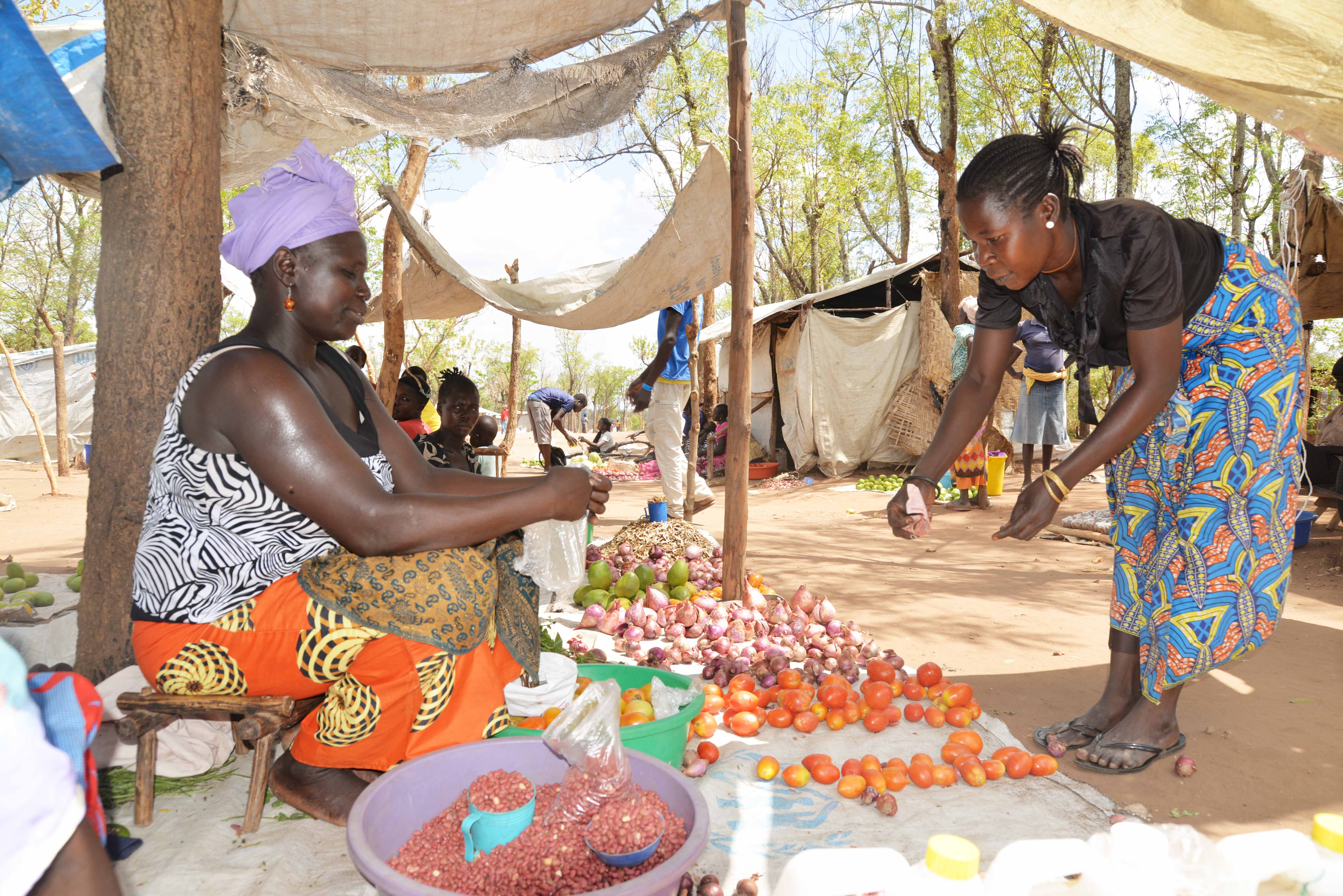 Yabang attending to her customer. She invested her cash for work money into selling tomatoes, onions and cooking oil