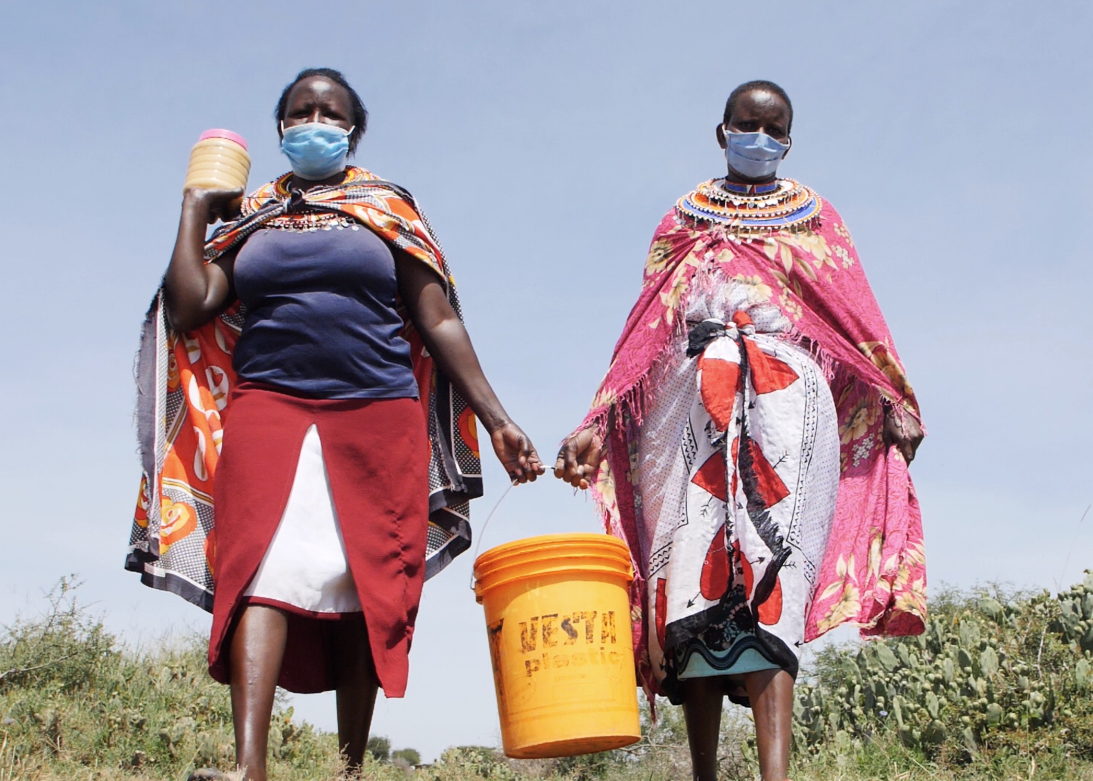 Annesia Putunoi and Margarate Saino carry raw honey from their apiary ready to sell to the cooperative.