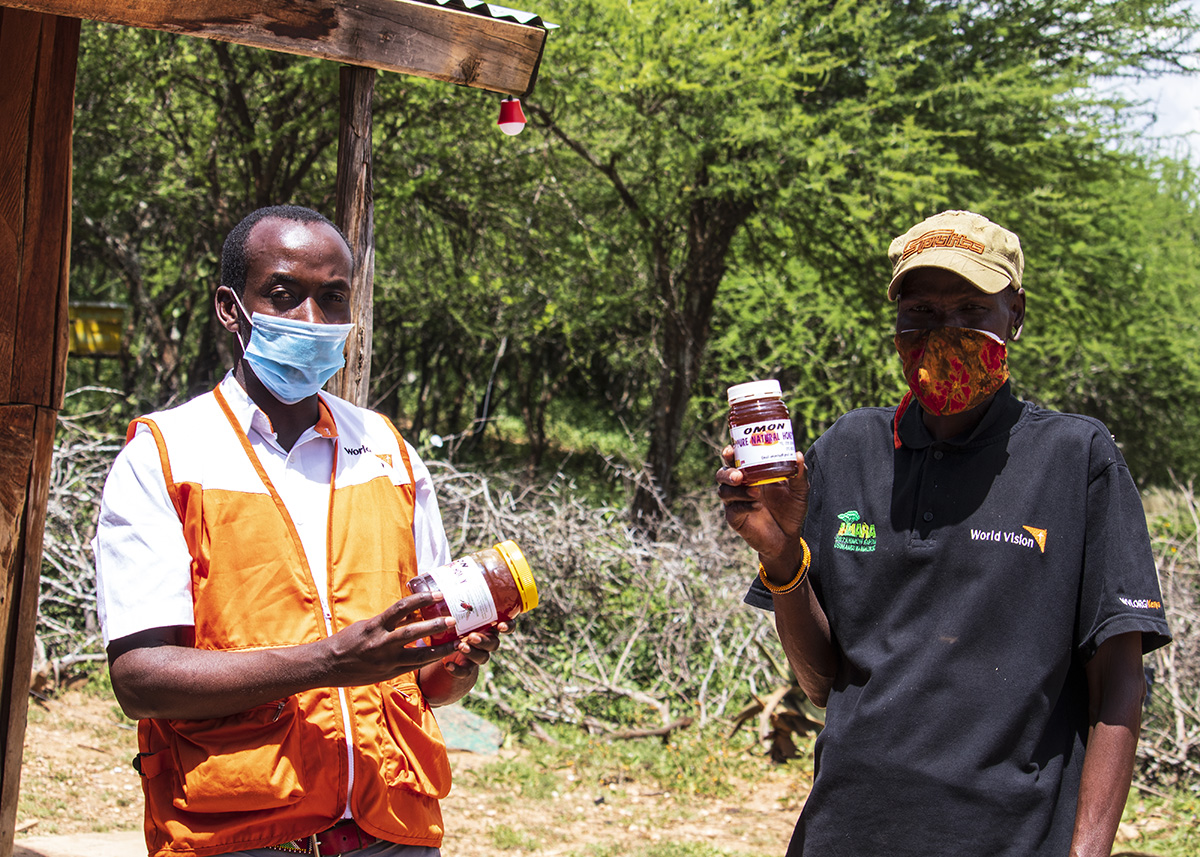 Tom Liloi hold packed honey with Livelihood specialist Joseph Ethekon