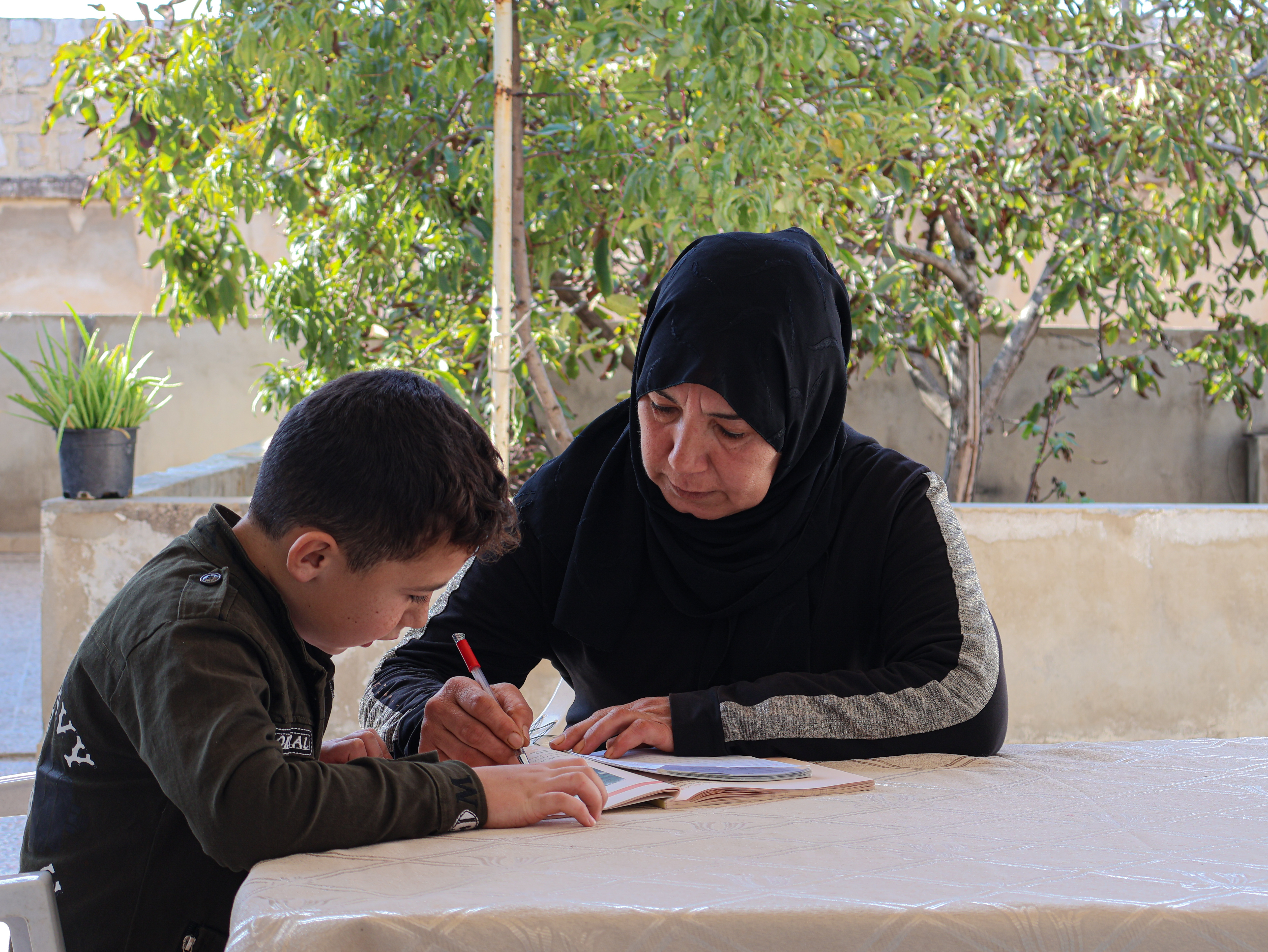 World Vision Syria Response Partner, Takaful Al Sham Samah helping her son with school.