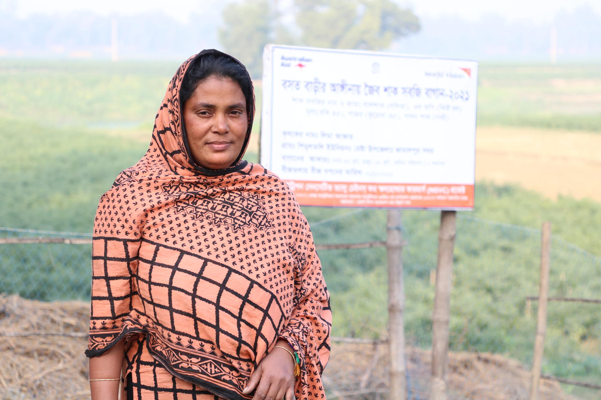 A woman stands in front of a sign.