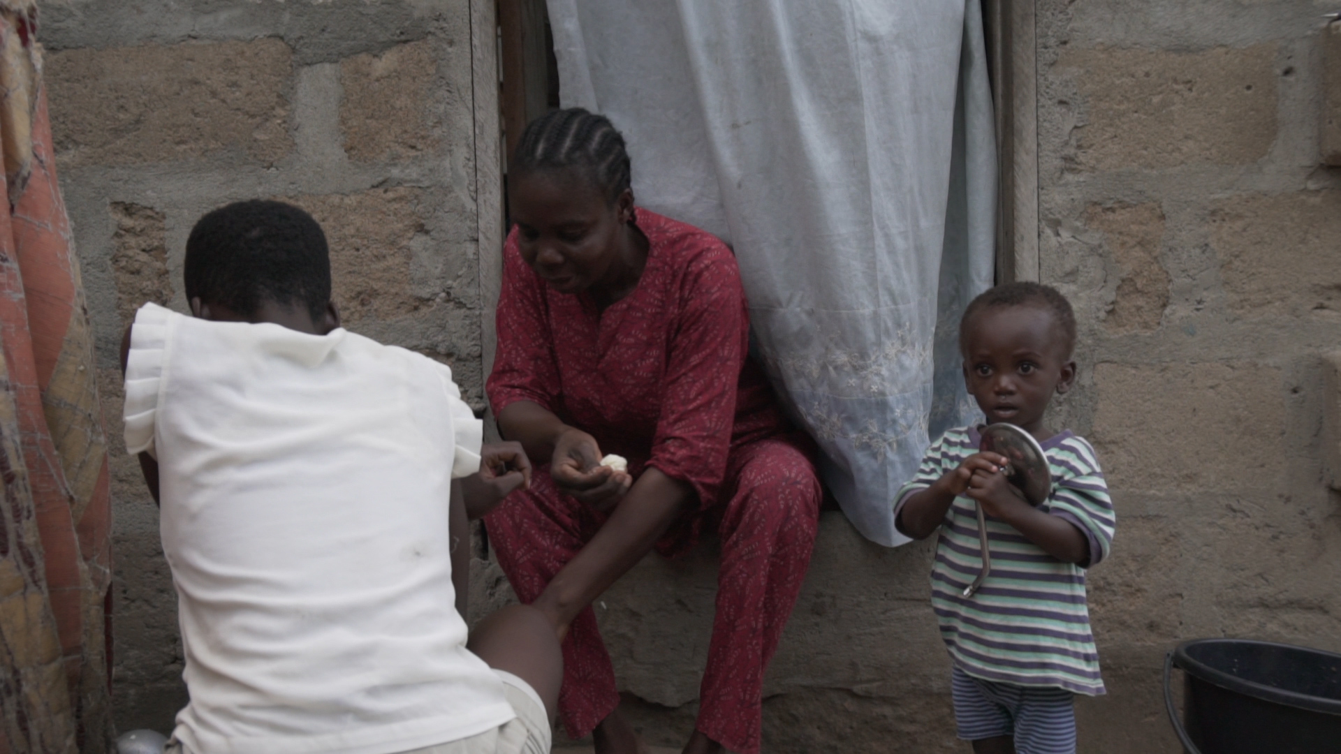 Adjoa and her mum eat dinner while Isaac looks at the camera