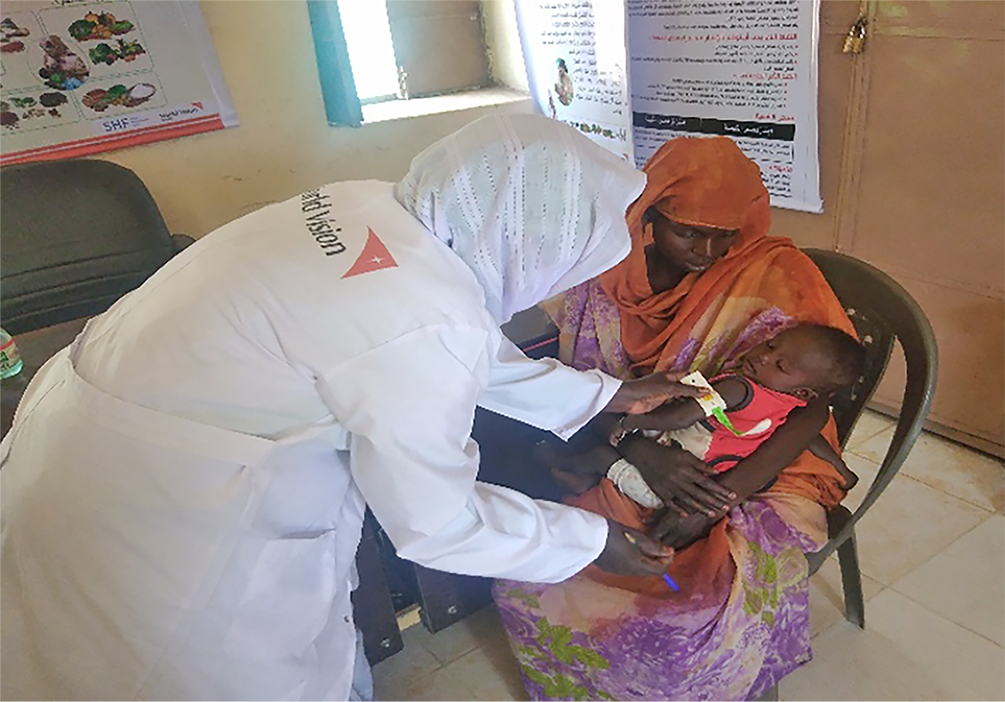 A nutrition specialist screens a child in Sudan for malnutrition