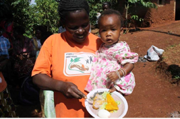 Annet, Joseph's wife feeds her 2-year-old son on Vitamin A rich organge flesh sweet potatoes.