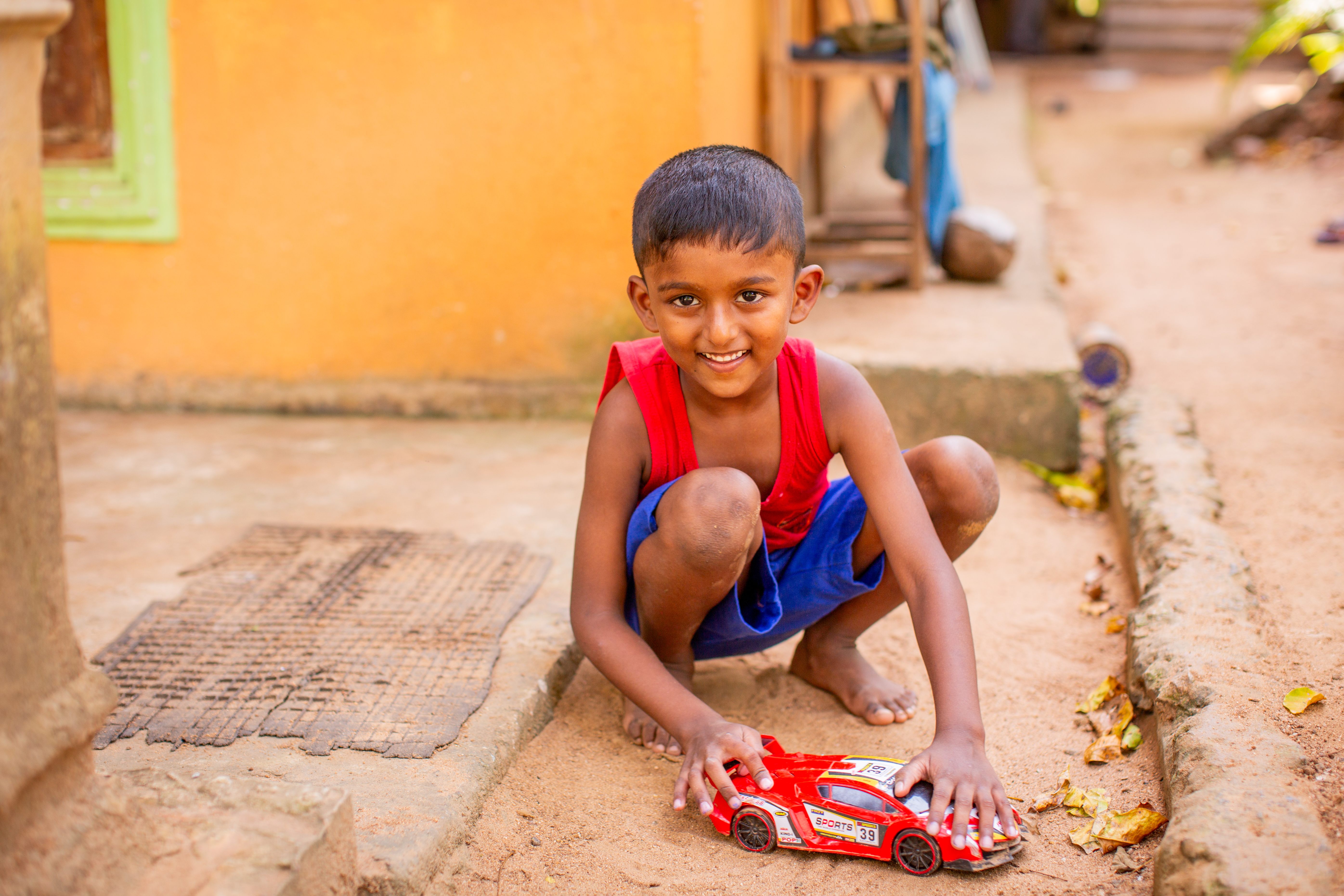 A child plays with a toy car outside a home in  Wanathawilluwa, Sri Lanka.