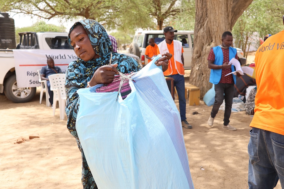 Une beneficiaire recevant le kit d'urgence de la main de l'équipe de World Vision