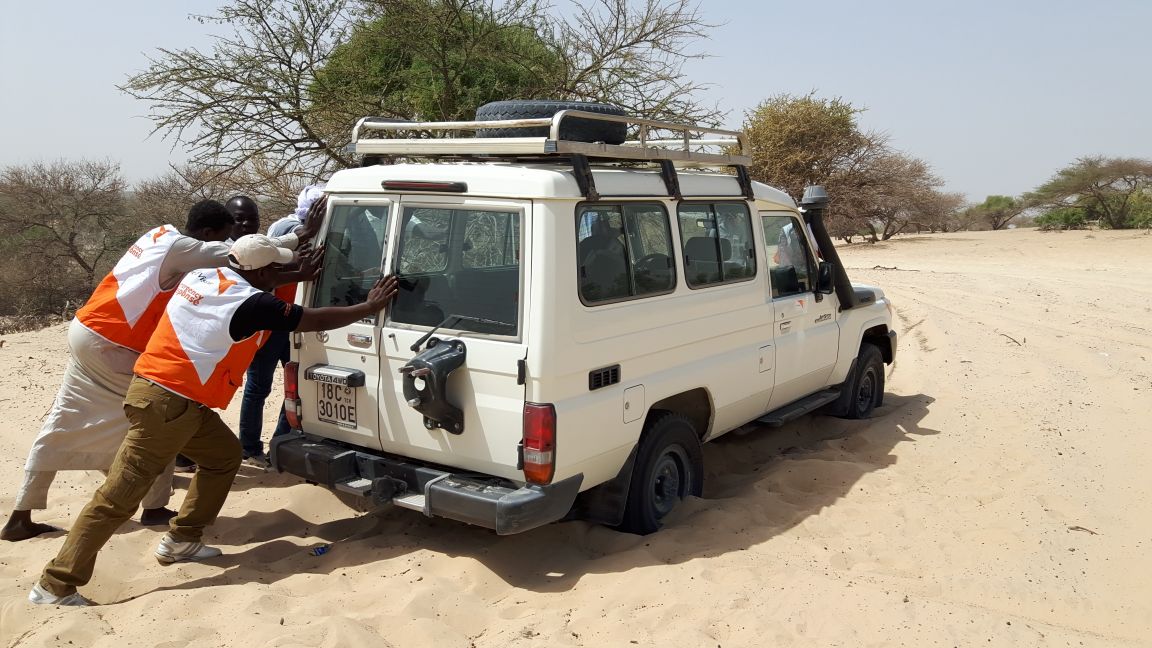 World Vision staff push their vehicle through sand to reach those in greatest need. 