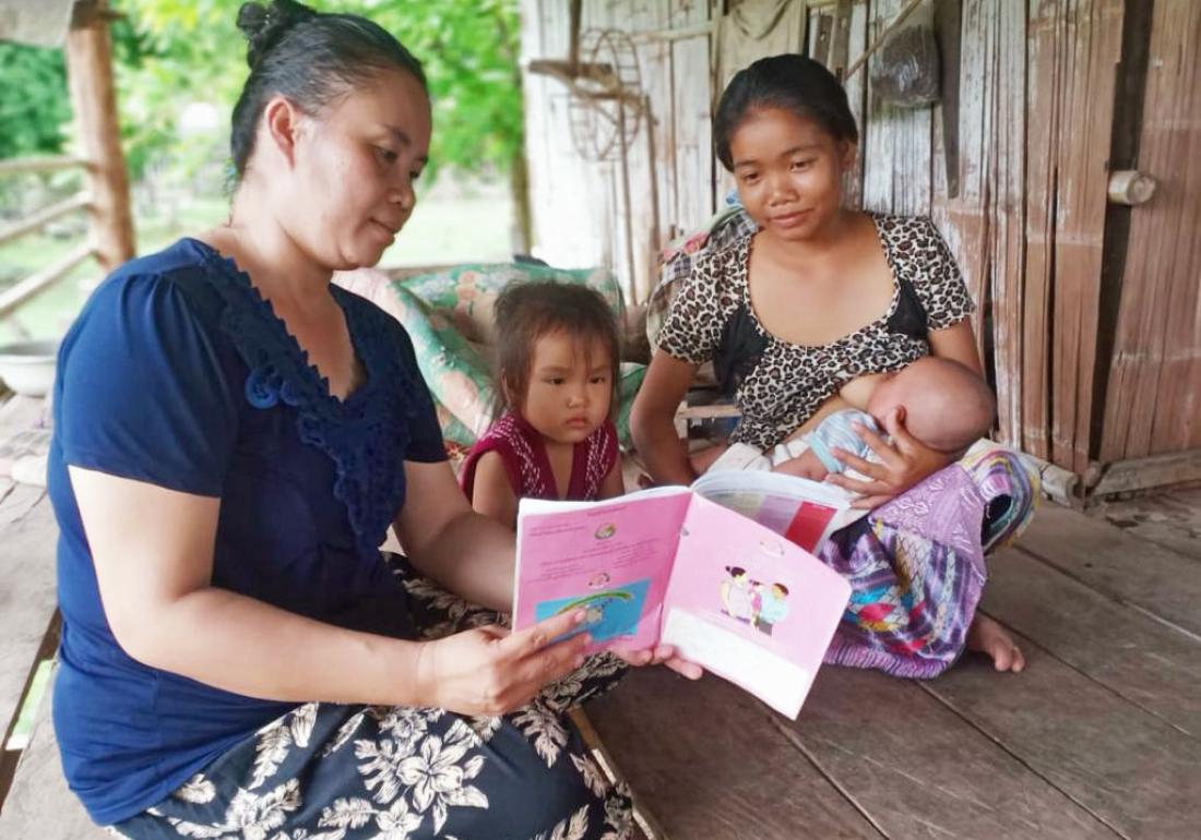 Lamphane breastfeeds as her children learn in Laos.