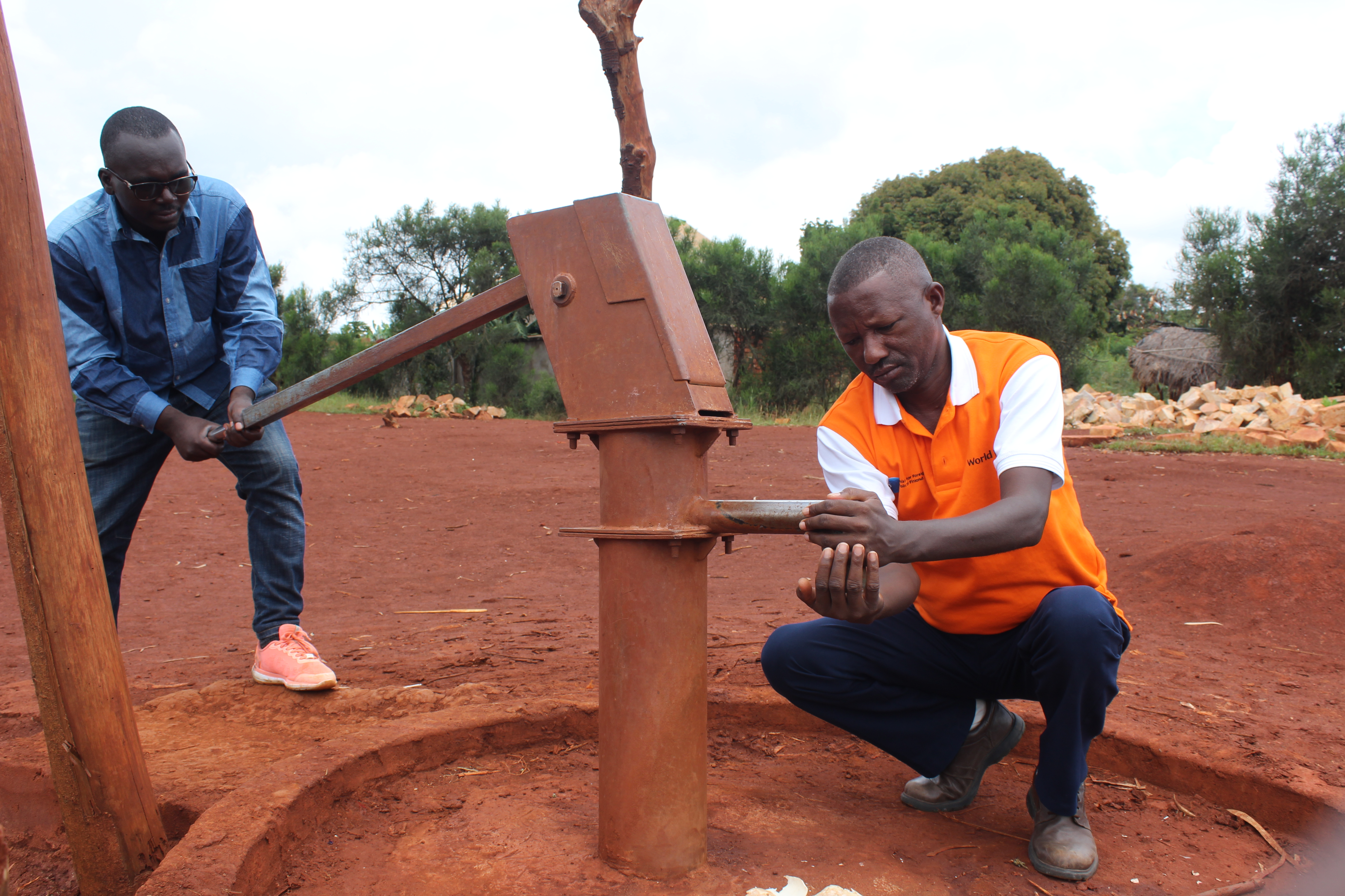 World Vision staff looking at a damaged borehole that Evelyne used to go to for water