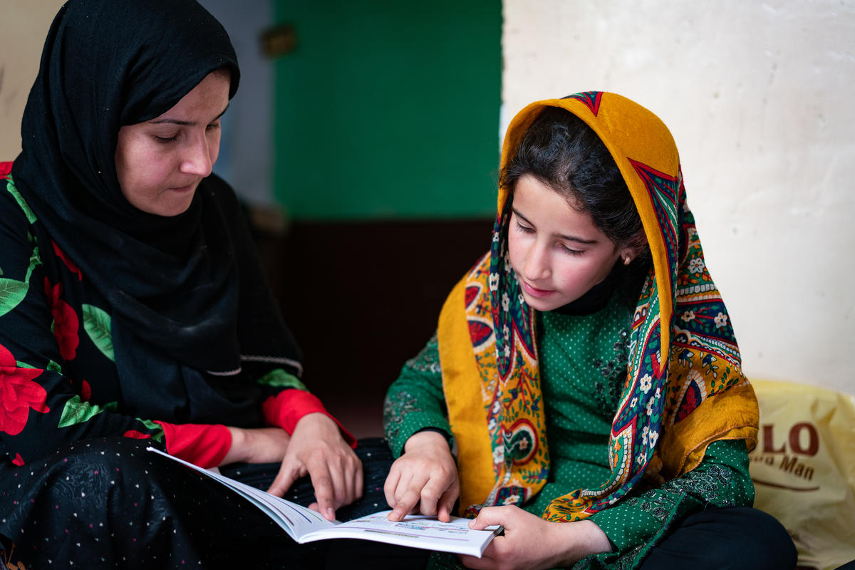 Rowaida helps her 11-year-old daughter Ilham read in Afghanistan, realising her dreams for a better future. Brett Tarver/World Vision