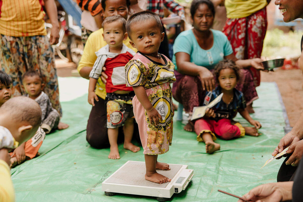Young child stands on a scale to have his weight checked in Cambodia
