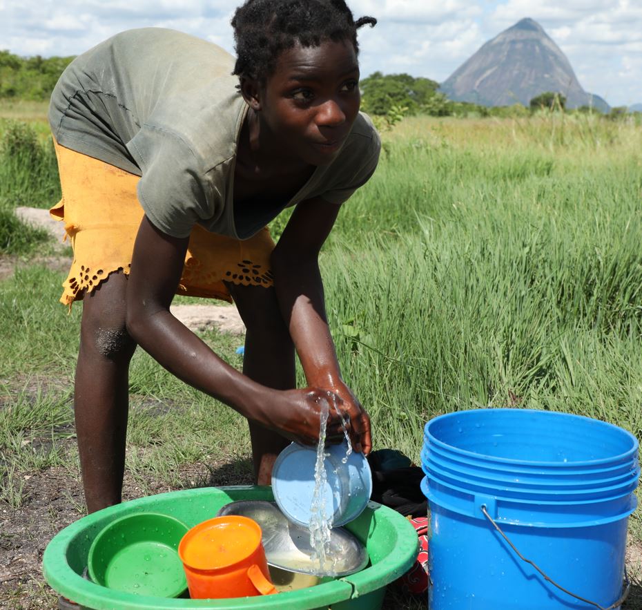 After collecting the water, Lizete washes the dishes which she brought to the lowland area