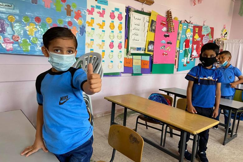 child in school with mask giving a thumbs up