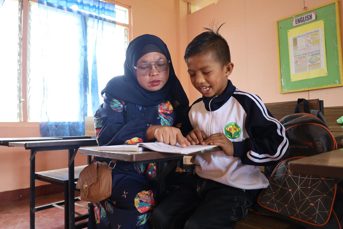 10-year-old Jubani, studies with the help of one of his teachers Rainisah