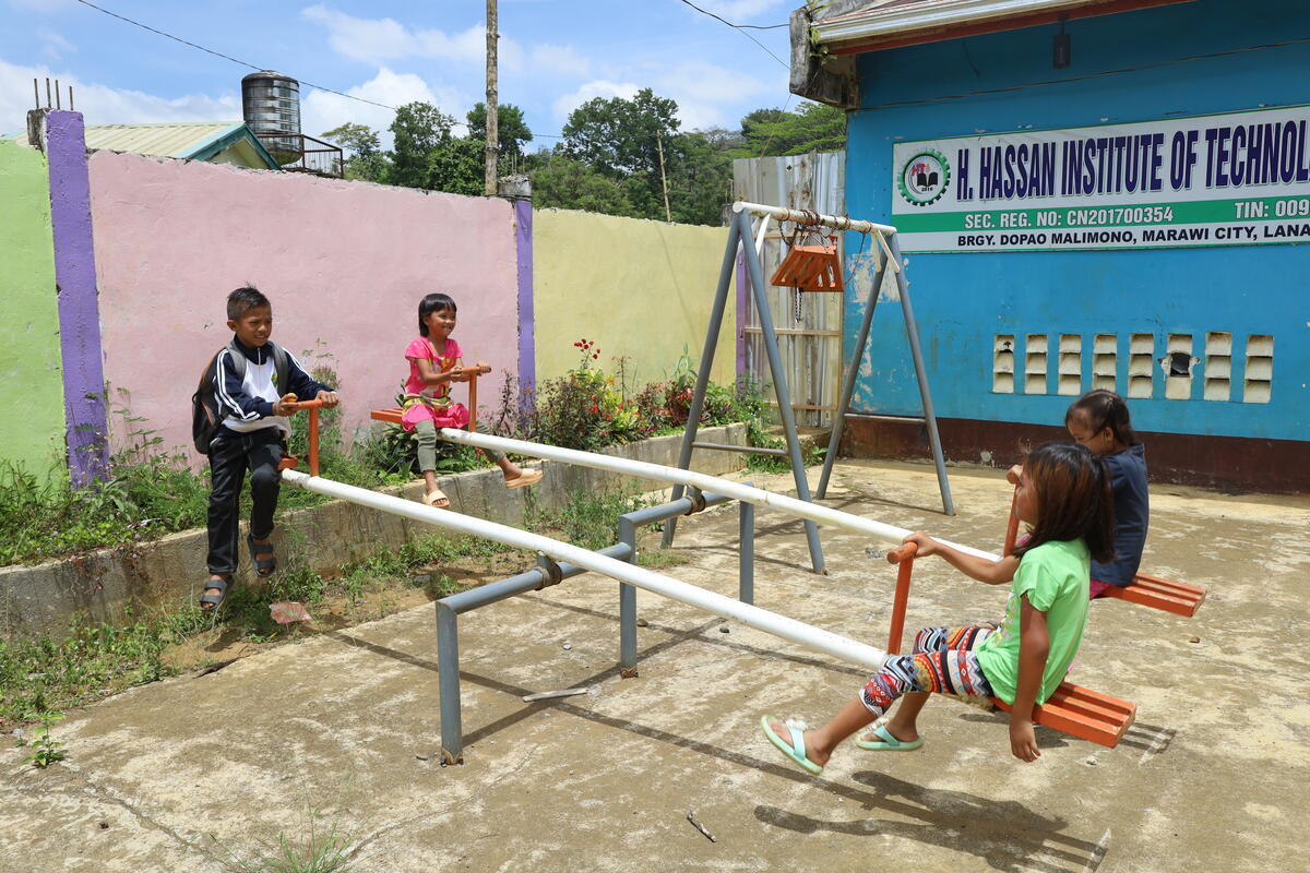 10-year-old Jubani (with the backpack), plays in a seesaw with some of his classmates.
