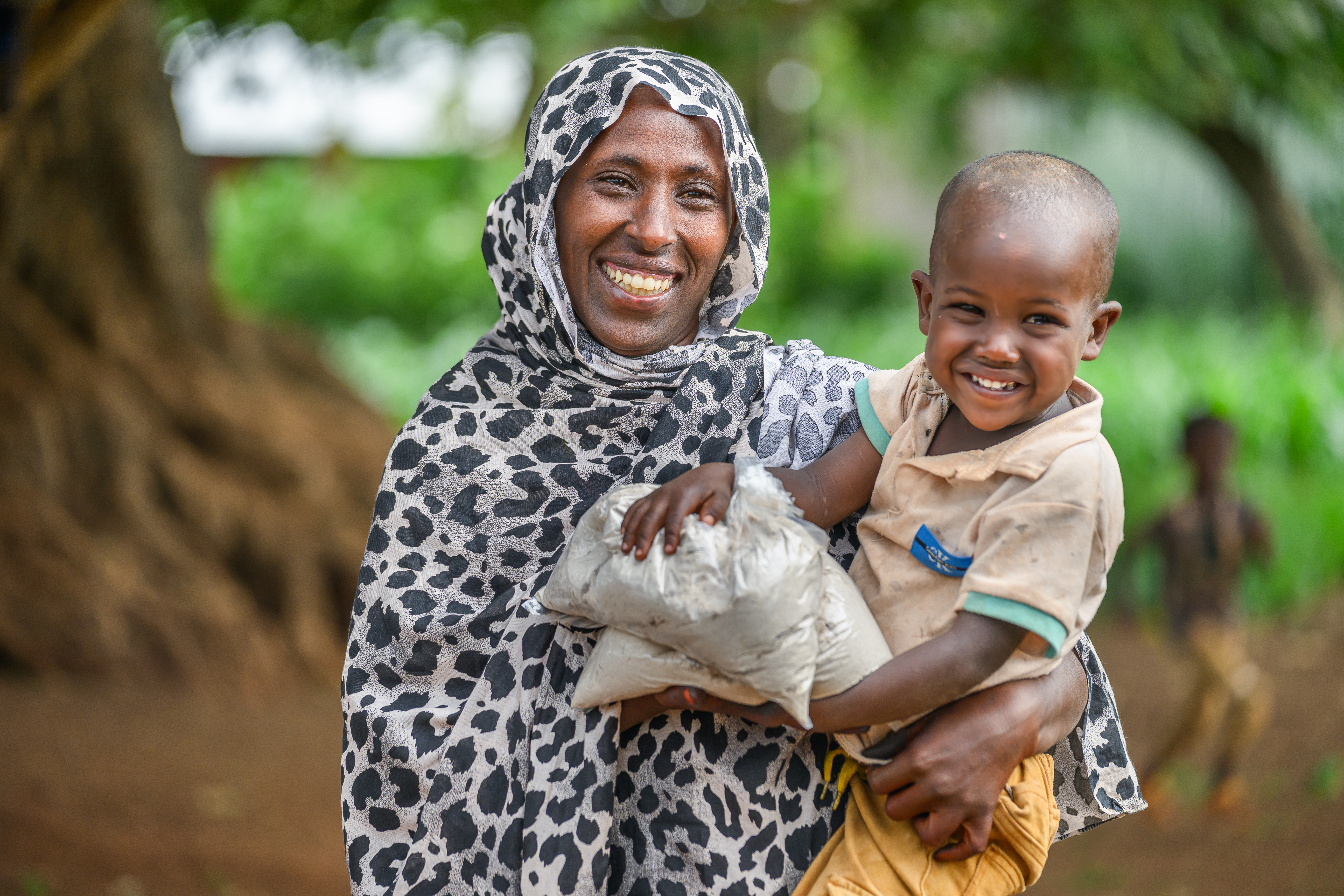 Laila Mumed, holding her son Arjoma Abrahim  and bags of flour that come from a SPIR II food distribution in Milino Village, Ethiopia.