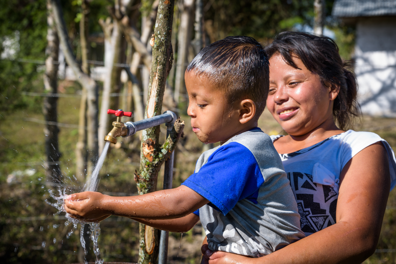 Child enjoys piped water spraying from a tap