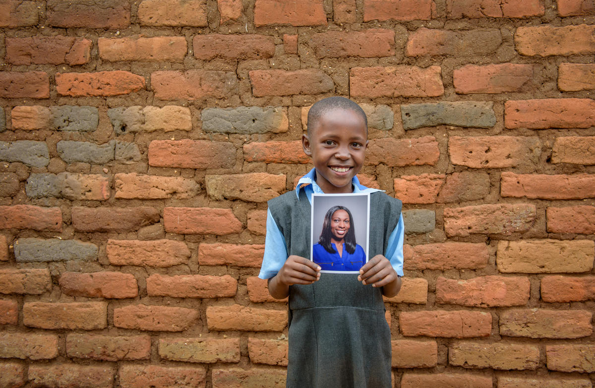 Nine-year-old Mary holds a picture of her sponsor, Yinka.