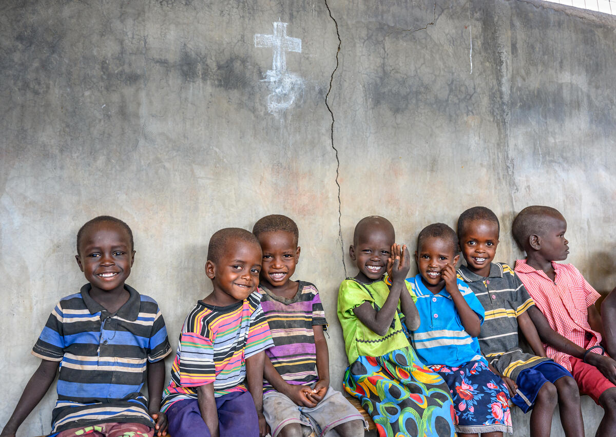 Children sit outside a church, smiling, in Kenya.