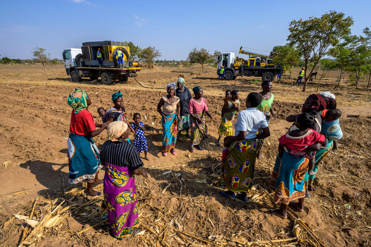 The local community in Malawi gather round to watch the drilling