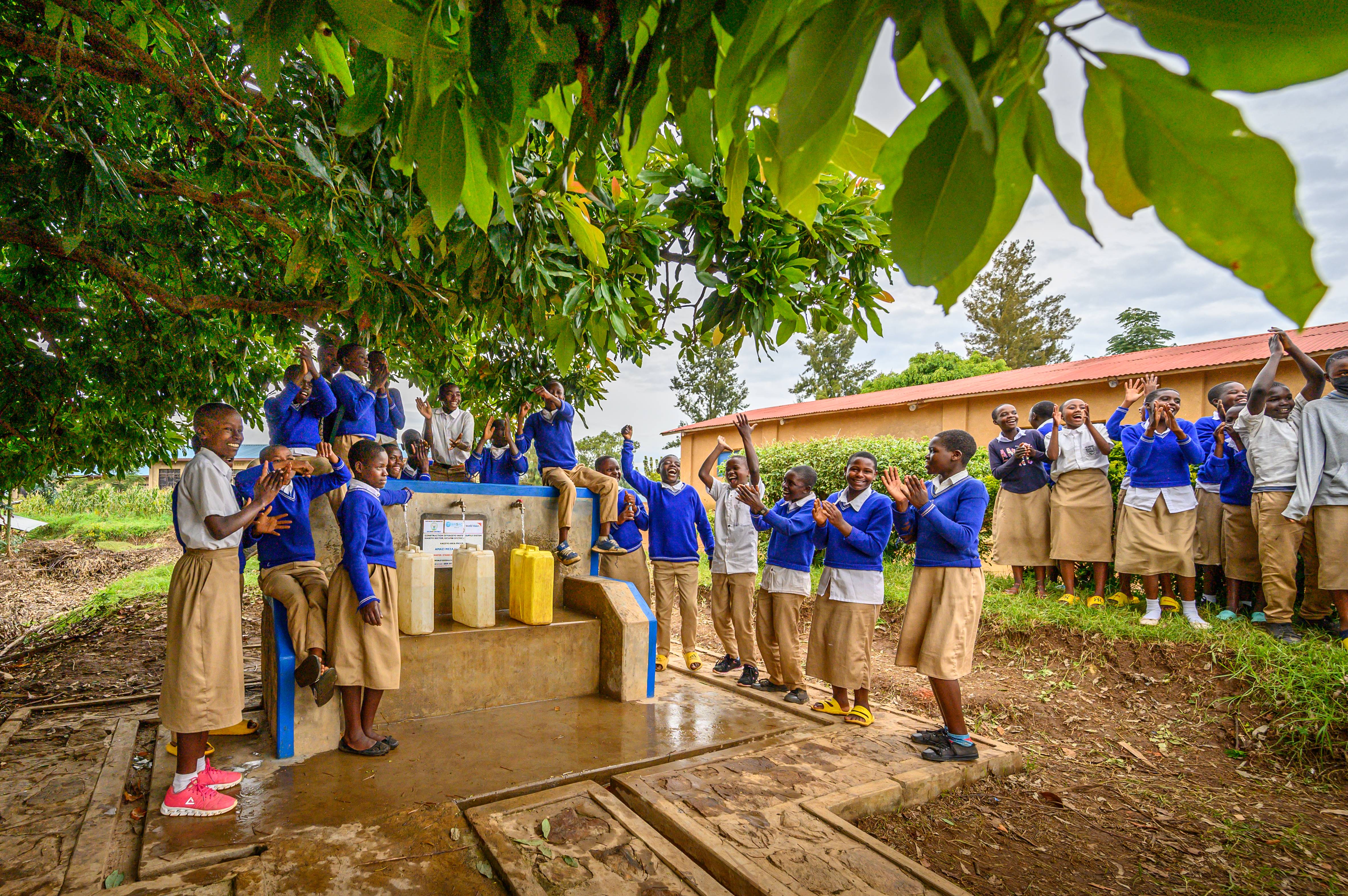 At a water point under an avocado tree, students at the Groupe Scolaire Muhondo school in Kageyo AP, Rwanda, celebrate their water system