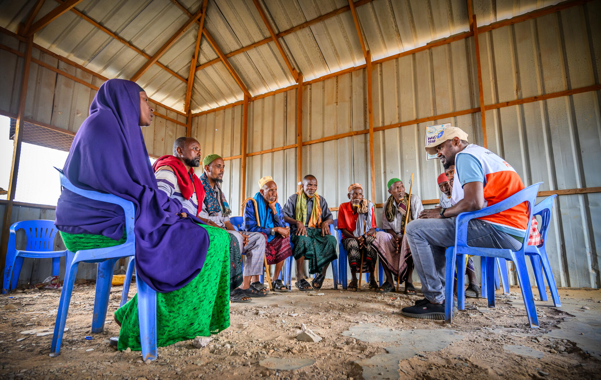 a group of faith leaders sit in plastic chairs in a semi circle
