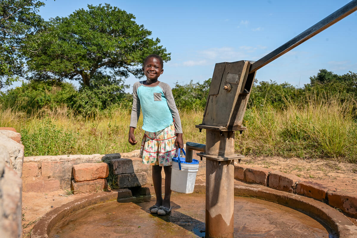 young boy fetches water from a pump