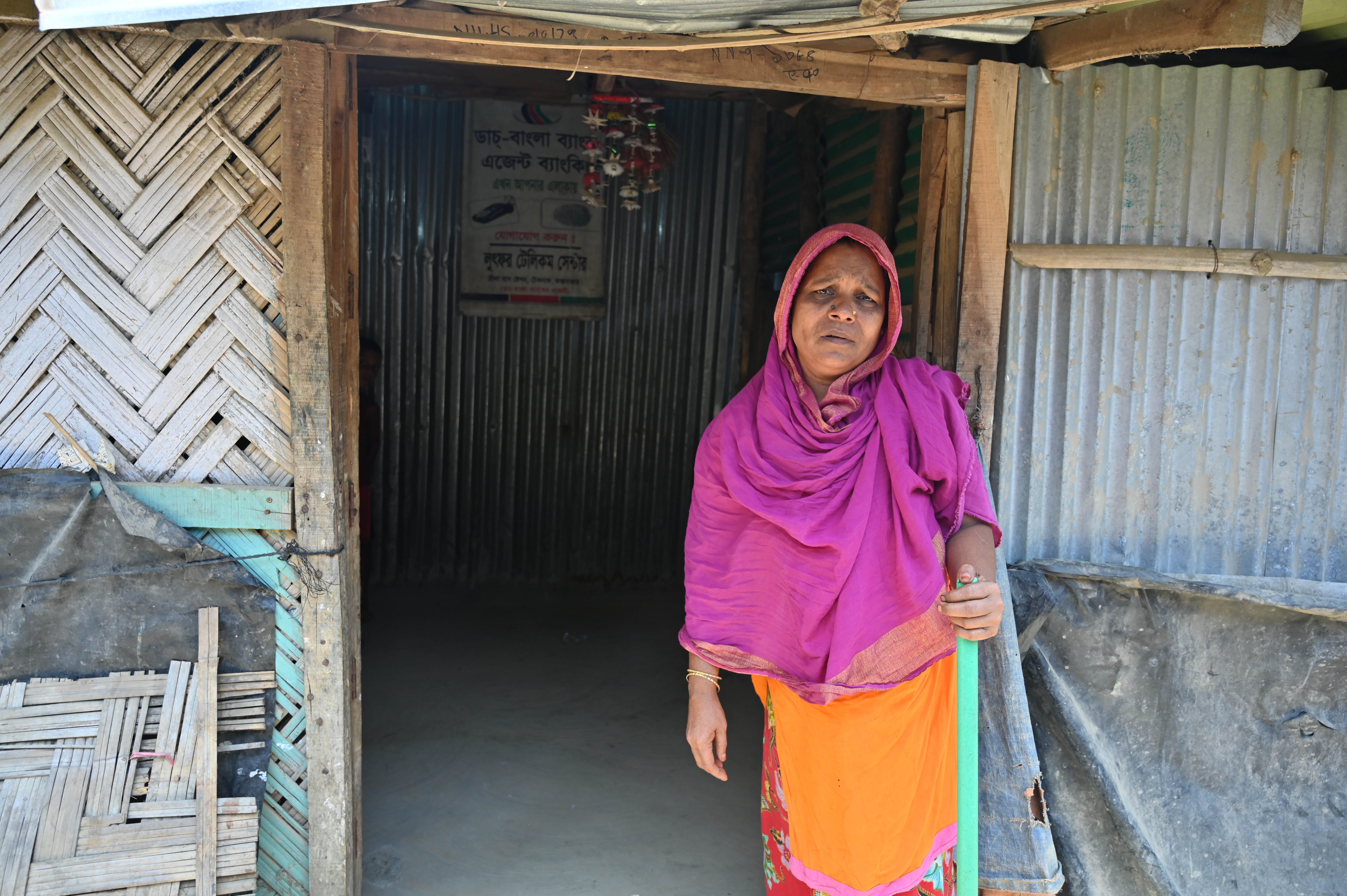 Monowara is a person with a physical disability and cannot walk without the support of a stick. She requires help from her elder son to carry her if she needs to leave her home.