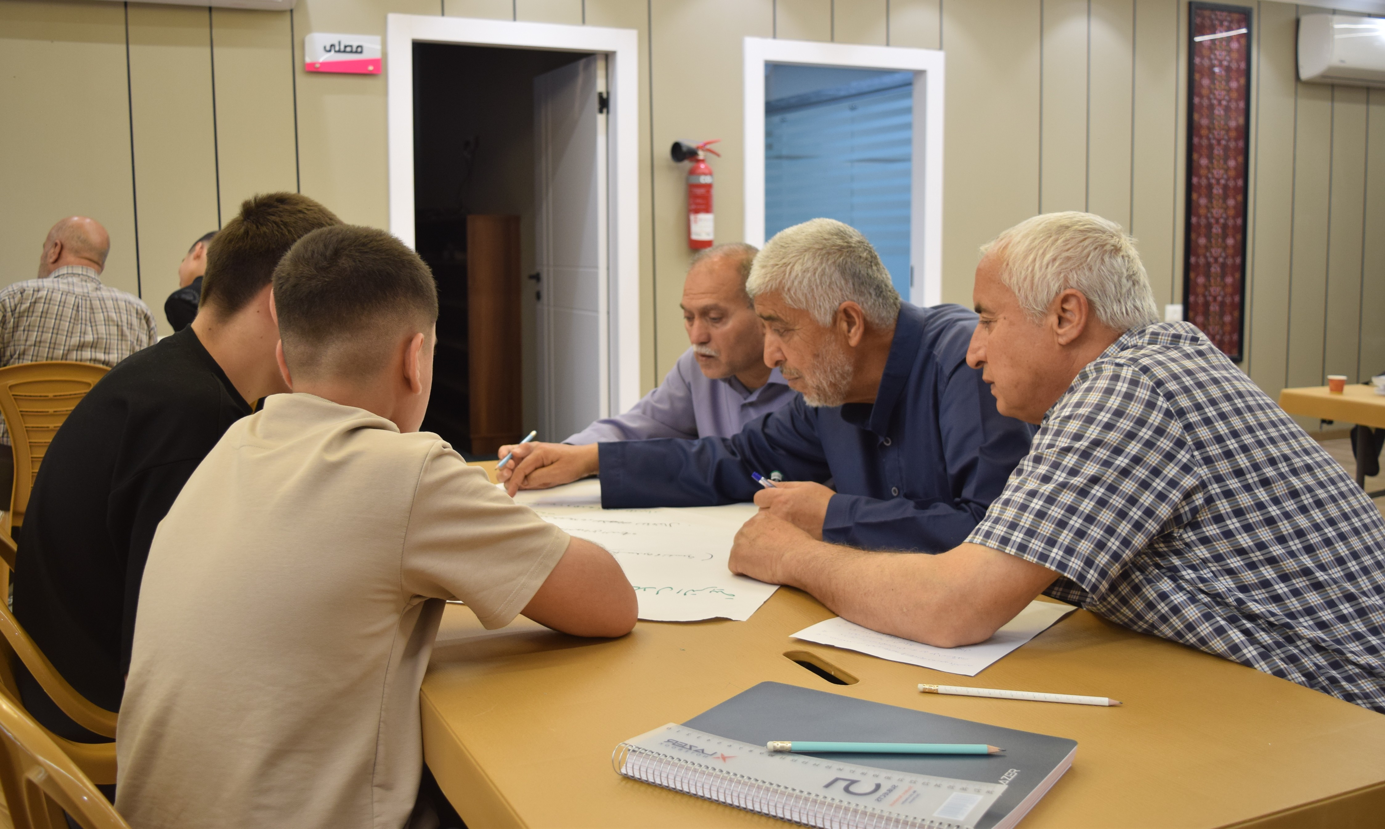 Participants from different generations work together during a Positive Discipline session in Qalqilya Governorate, creating a shared space for dialogue, learning and stronger relationships between fathers and adolescents.