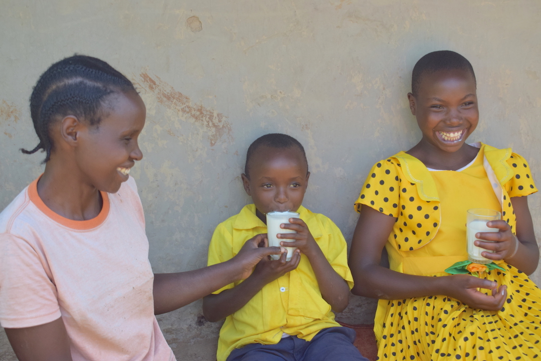 Left-Right: Annah, her Child Steven and sister Cynthia enjoying milk from cows that were bought with profit made from the family's brick making business in Nyamusi, Kenya. ©World Vision Photo/Sarah Ooko.