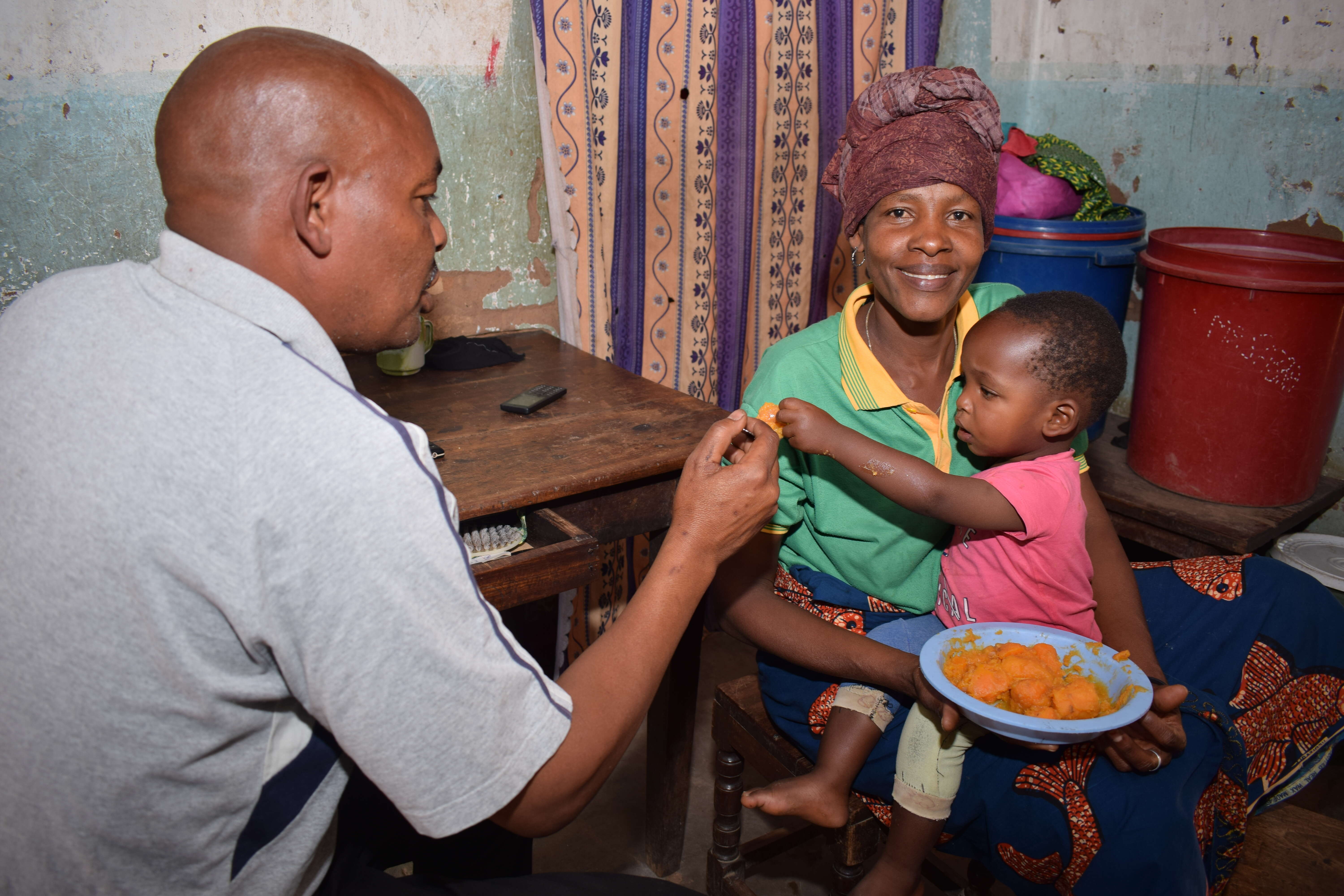 A family man feeds a child at  his home town in Ihanja, Singida region