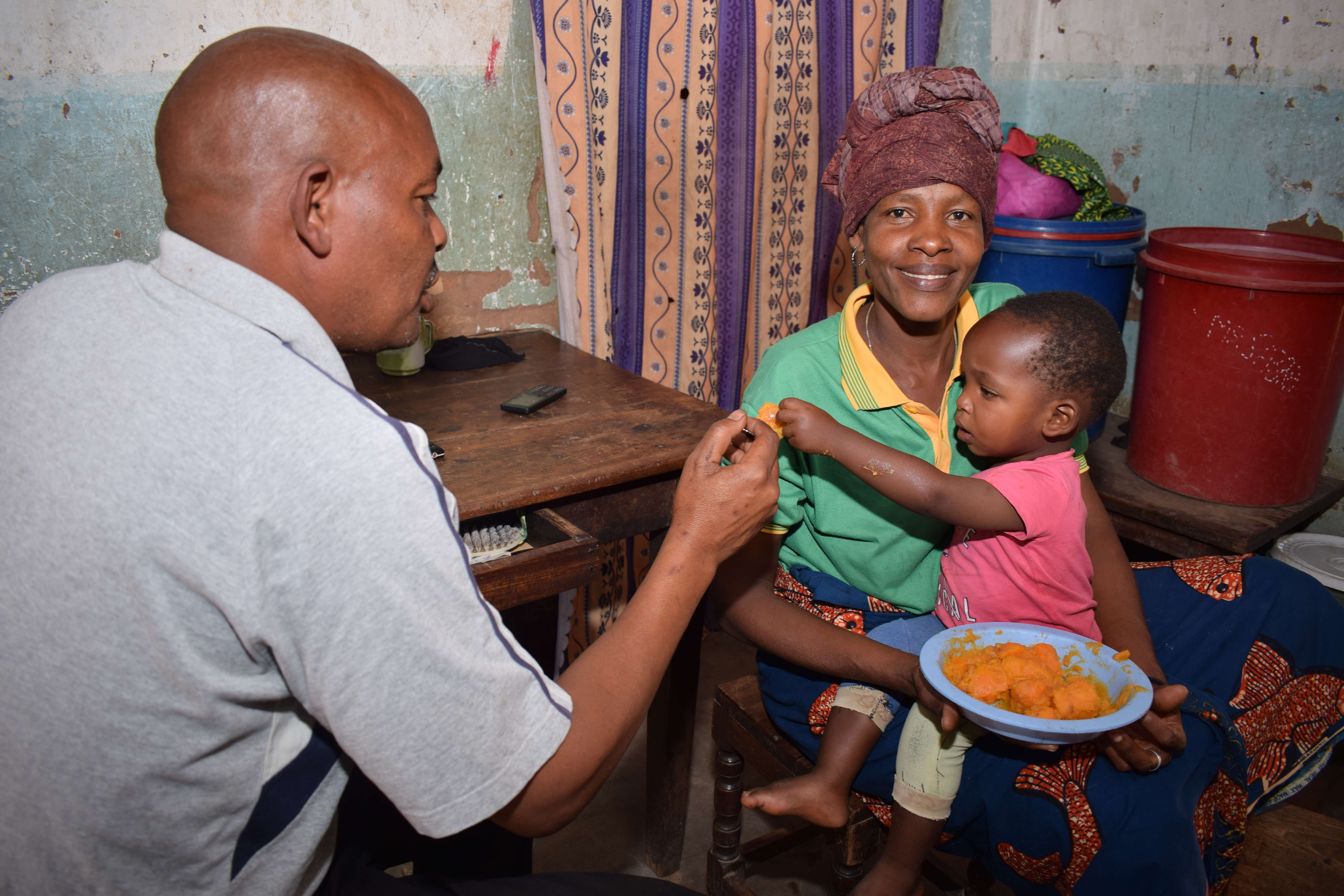 A family man feeds a child at his home town in Ihanja, Singida region