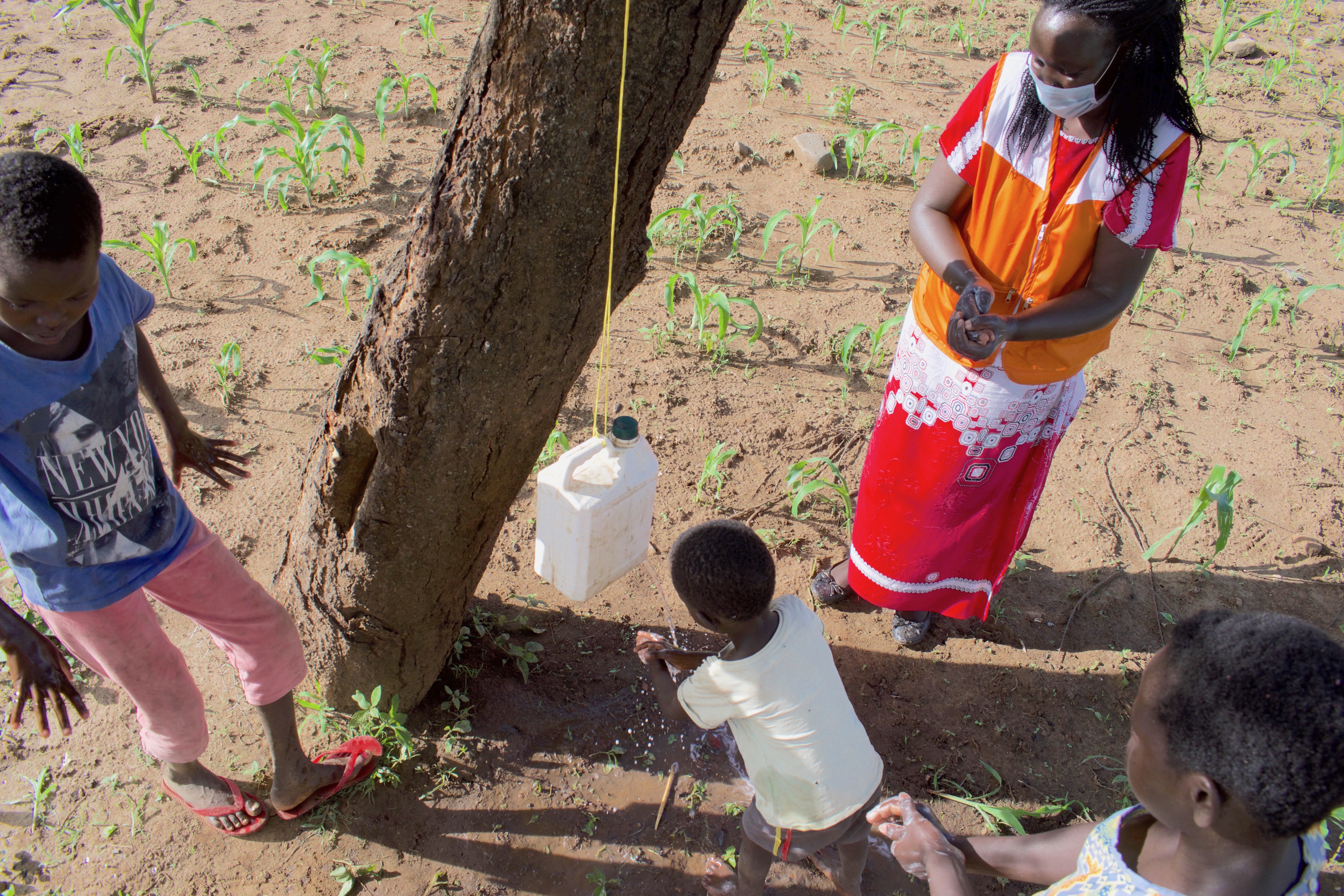 Vision Kenya’s Pascalyne Rutto demonstrates to Salina and James children how to clean their hands so as to prevent COVID-19