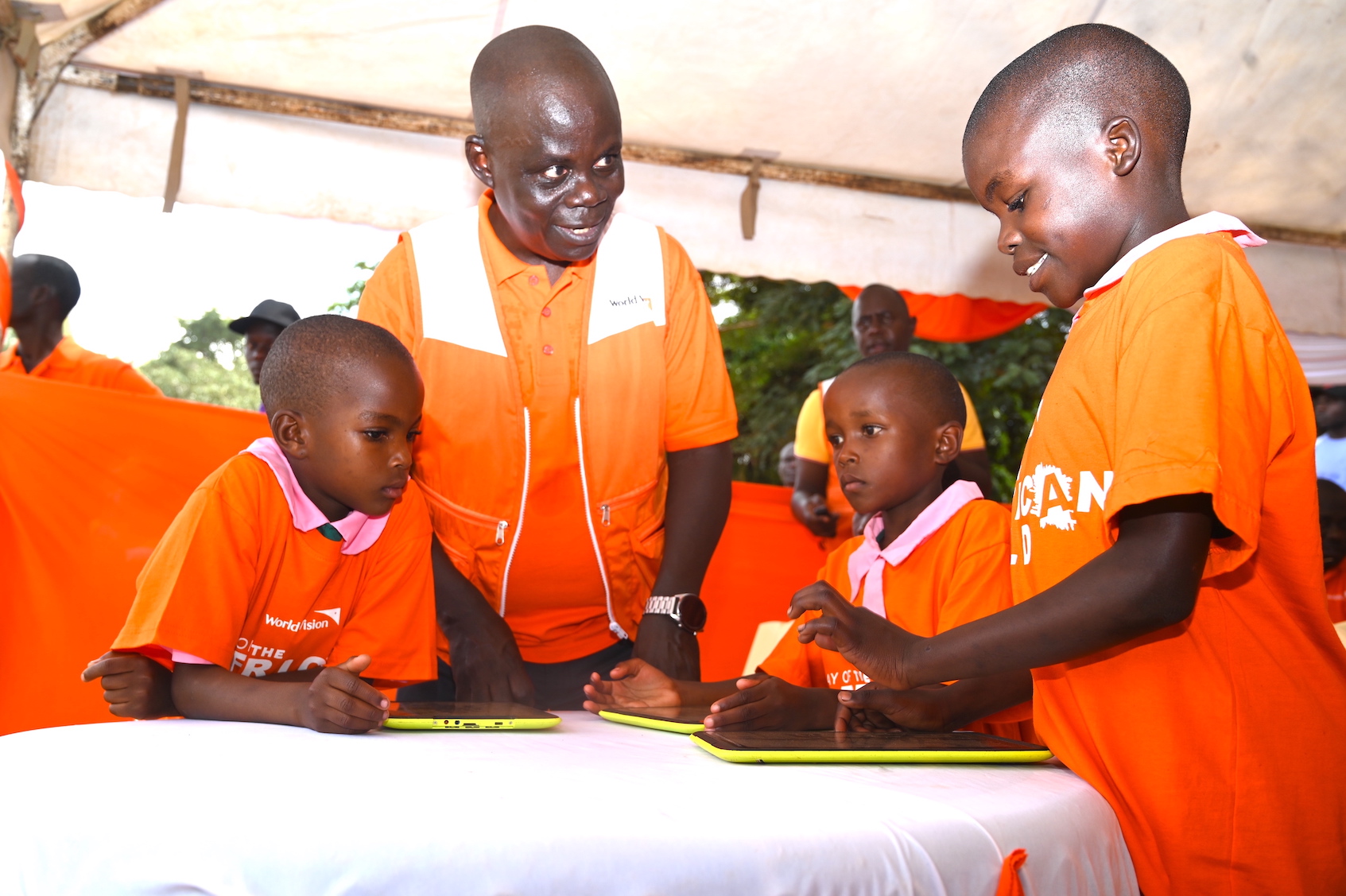 Gilbert Kamanga (centre), the National Director of World Vision Kenya interacts with children who enjoy e-learning opportunities.Digital technologies are enabling children in rural areas to access quality learning resources in Western Kenya. ©World Vision Photo/Allan Wekesa.
