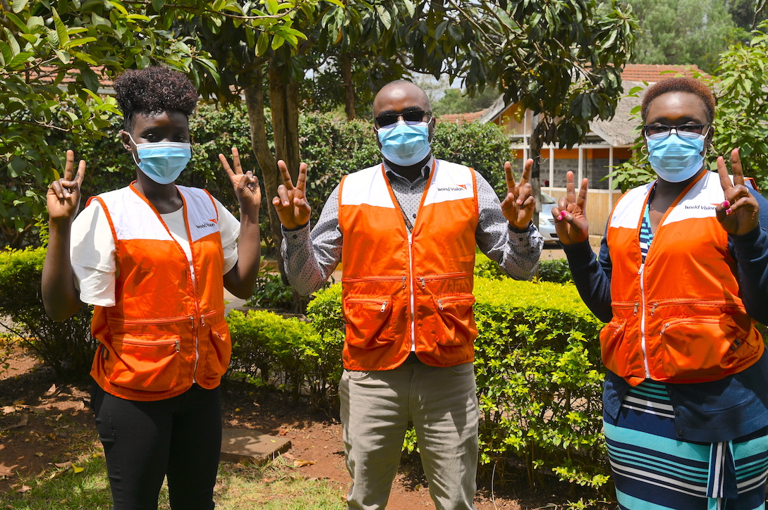 World Vision Kenya staff that have been vaccinated join the 'V-for vaccinated' campaign. Just as many Kenyans who have received the vaccine, they are glad that it will reduce their chances of getting the disease. World Vision Photo/Sarah Ooko.