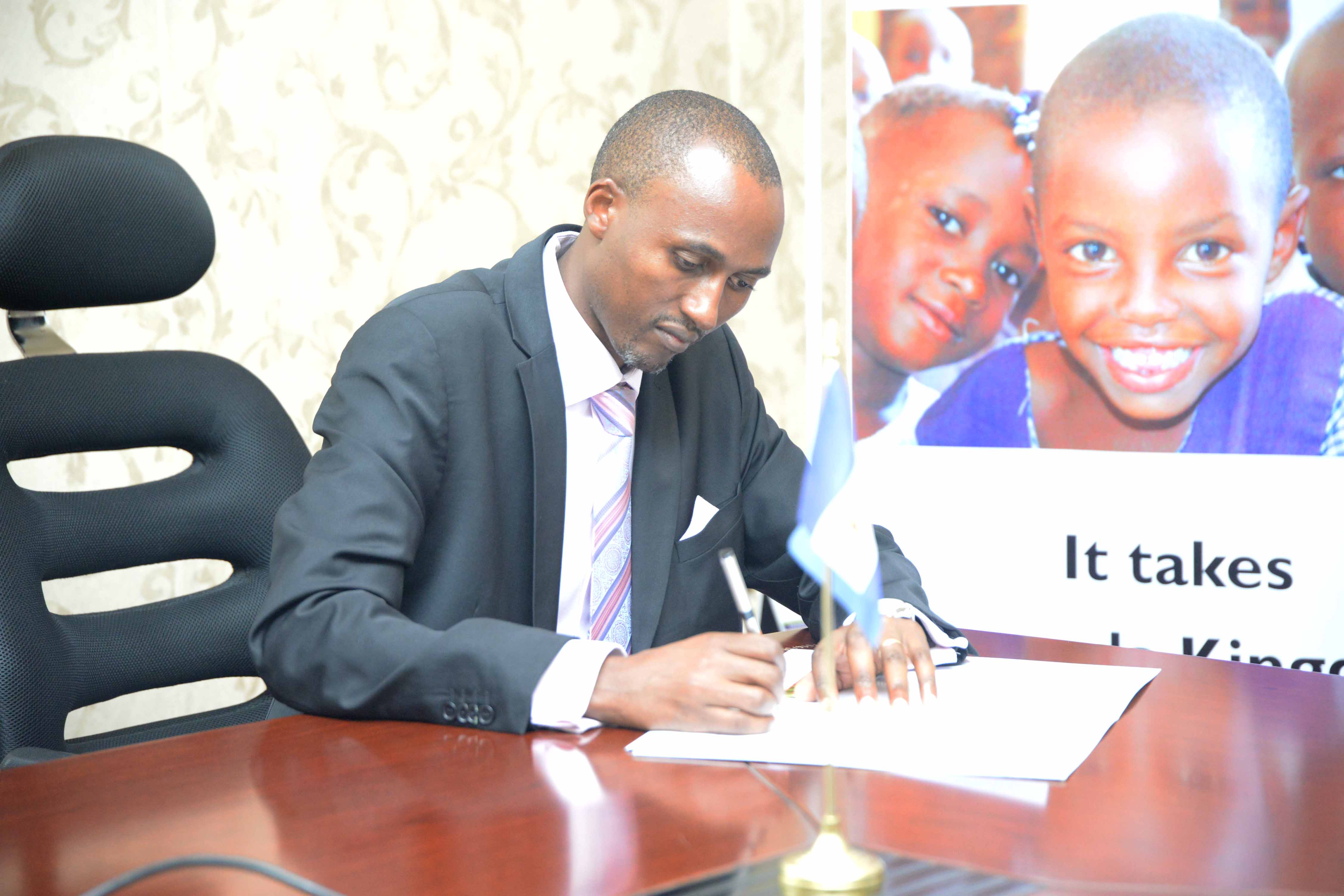 Jeremiah Nyagah, operations director for World Vision in Uganda signs the MOU between World Vision and the Buganda kingdom