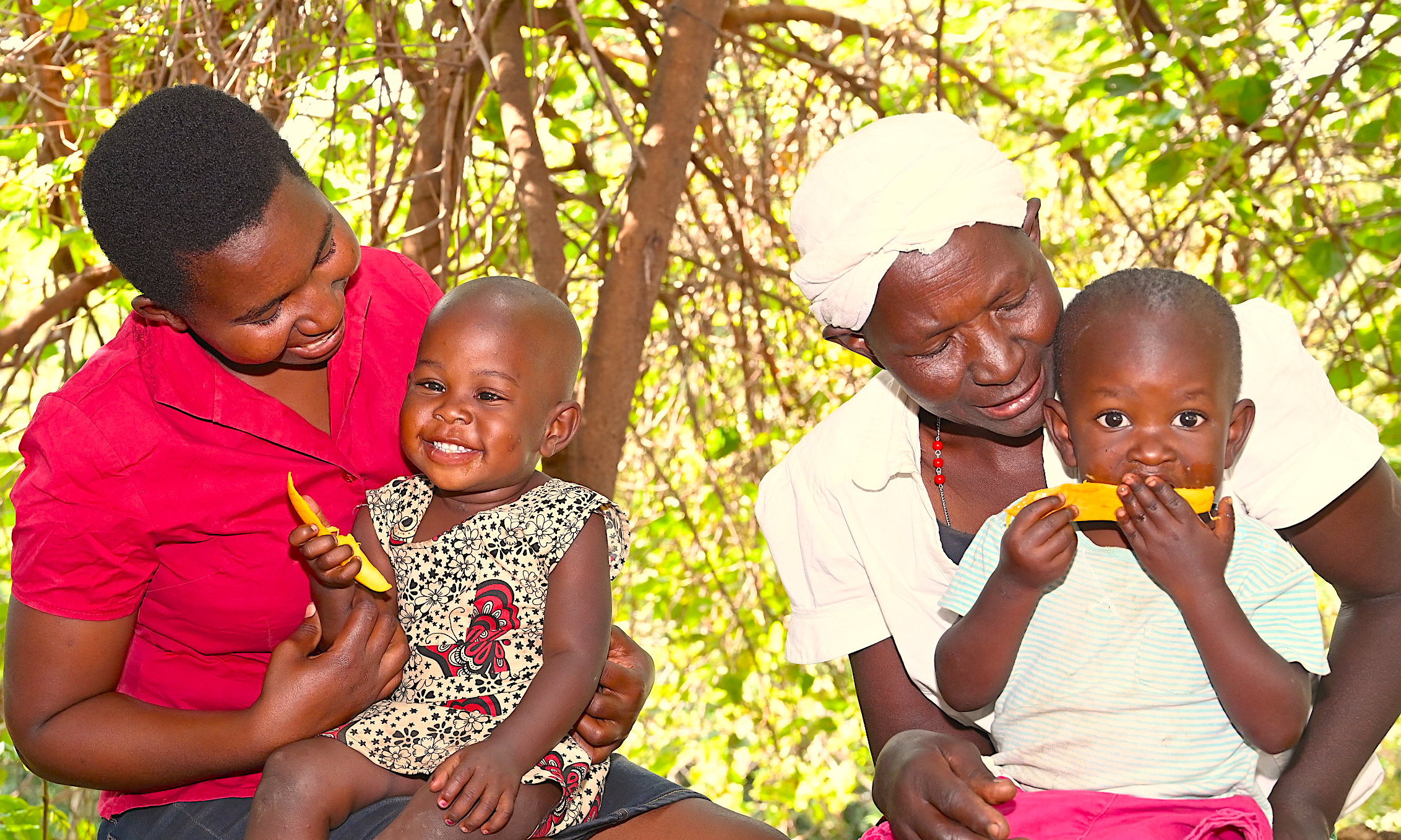 Salome, her daughter Alice and grandchildren enjoy mangoes harvested from trees in their farm.