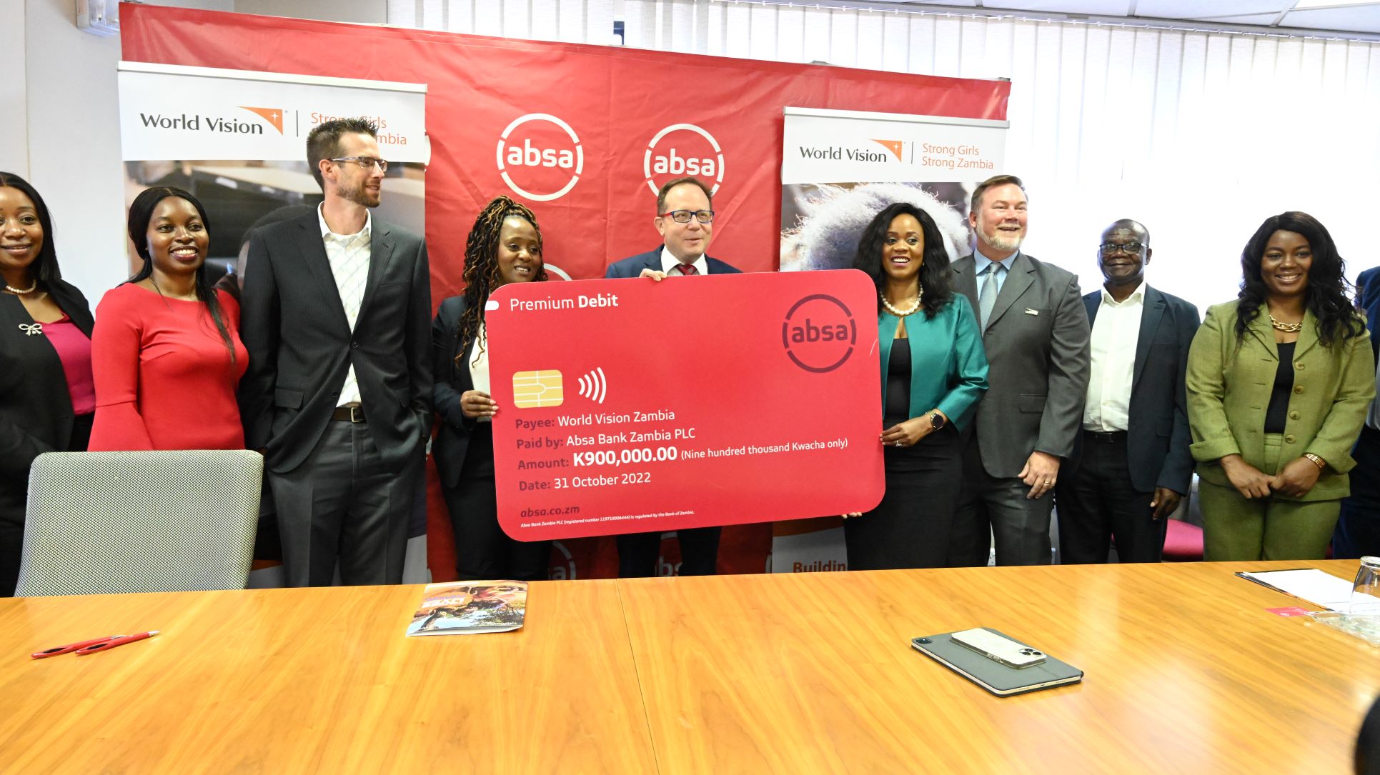 World Vision Zambia and Absa Bank Zambia representatives pose with the dummy cheque during the MoU signing ceremony.
