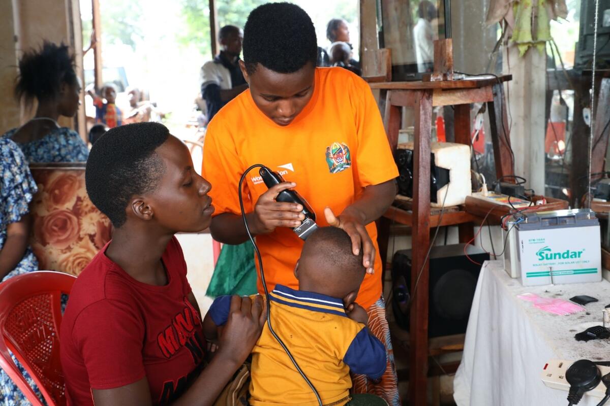 young girl uses a razor to cut the hair of a child 