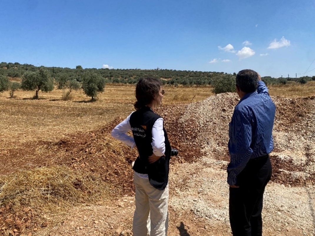 Member of the Council village of Qusrah standing with World Vision staff in front of mount of soil 