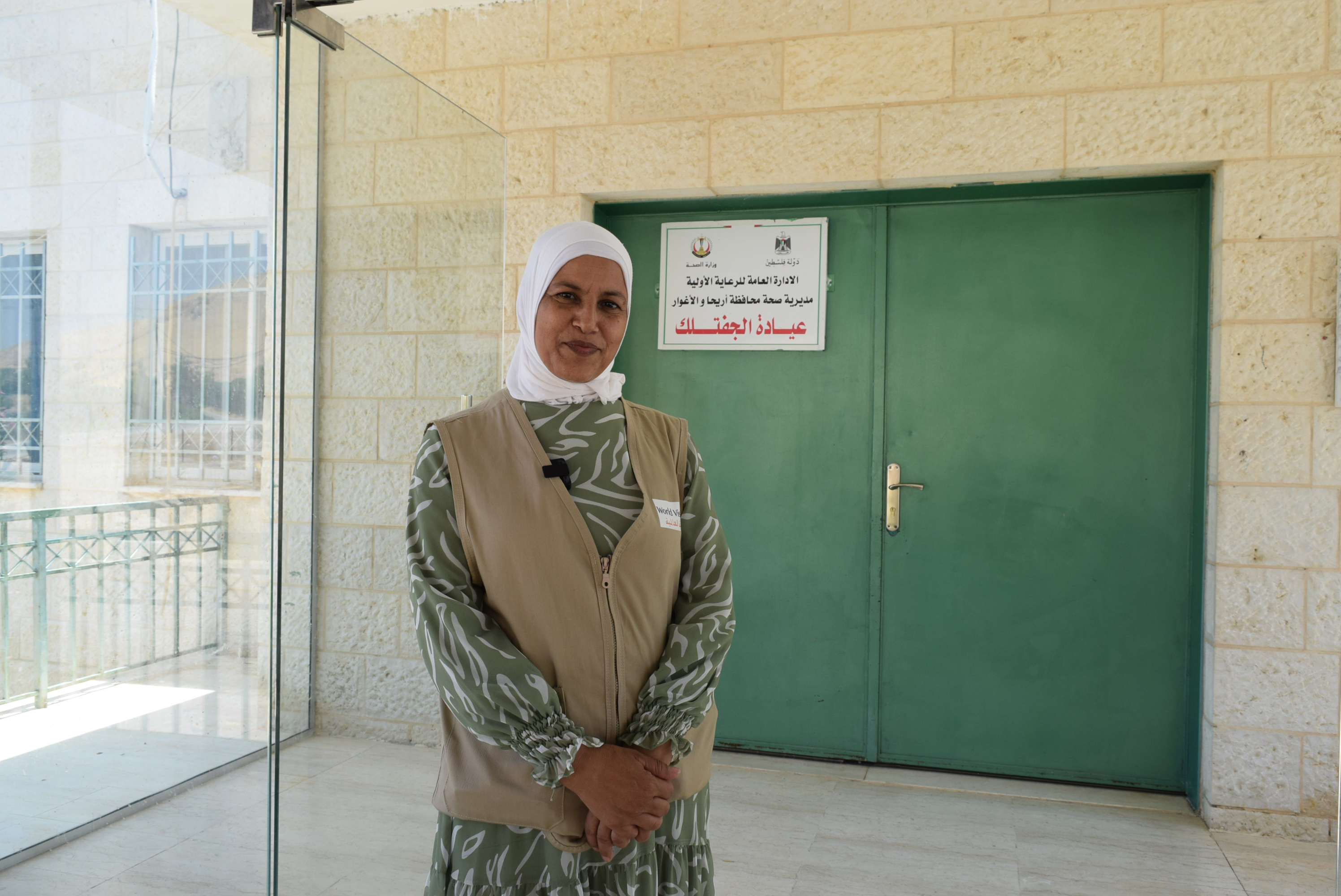 World Vision community volunteer standing in front of a local clinic