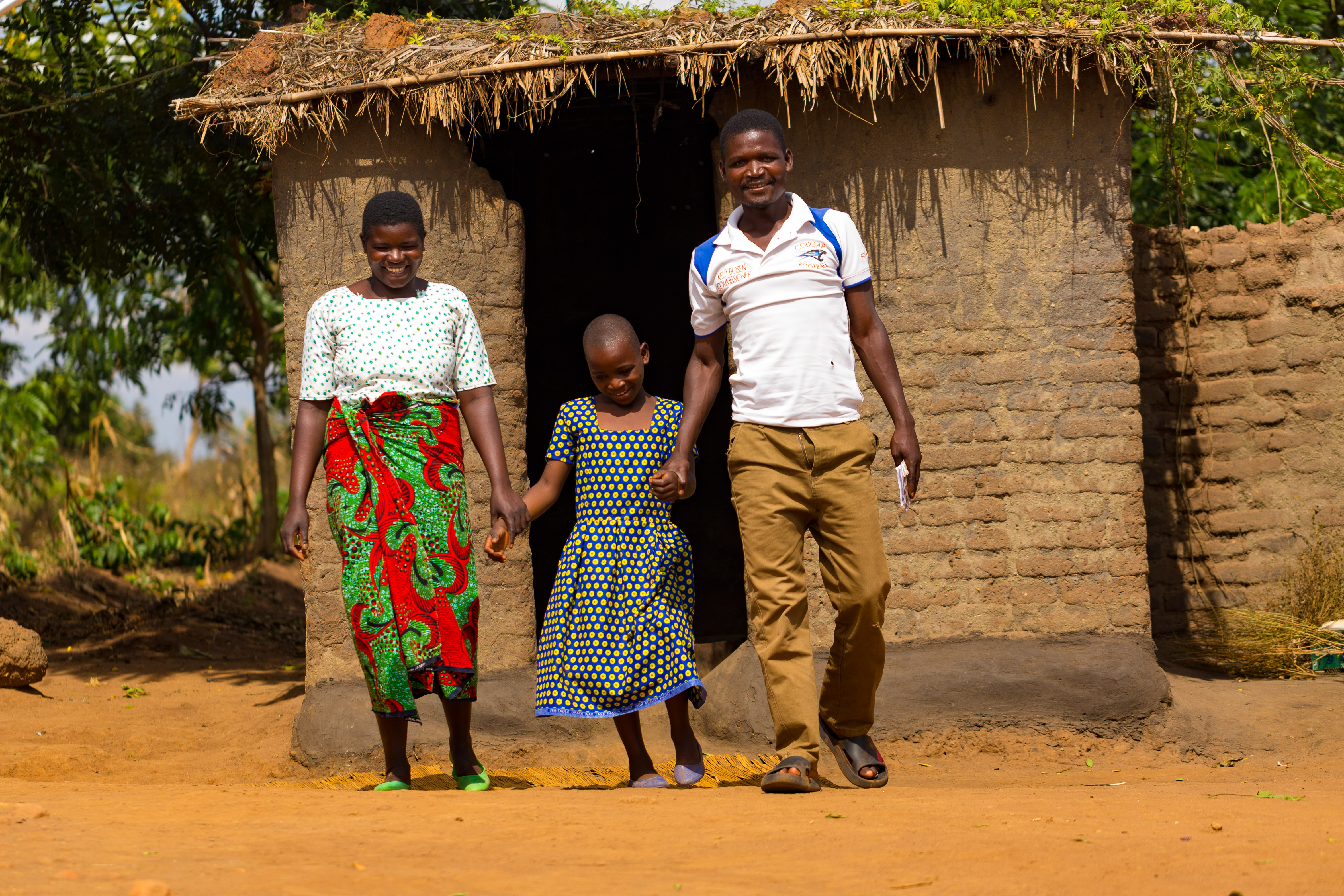 Mphambano and his wife Leonisa standing with Deborah, 9, in front of their house.