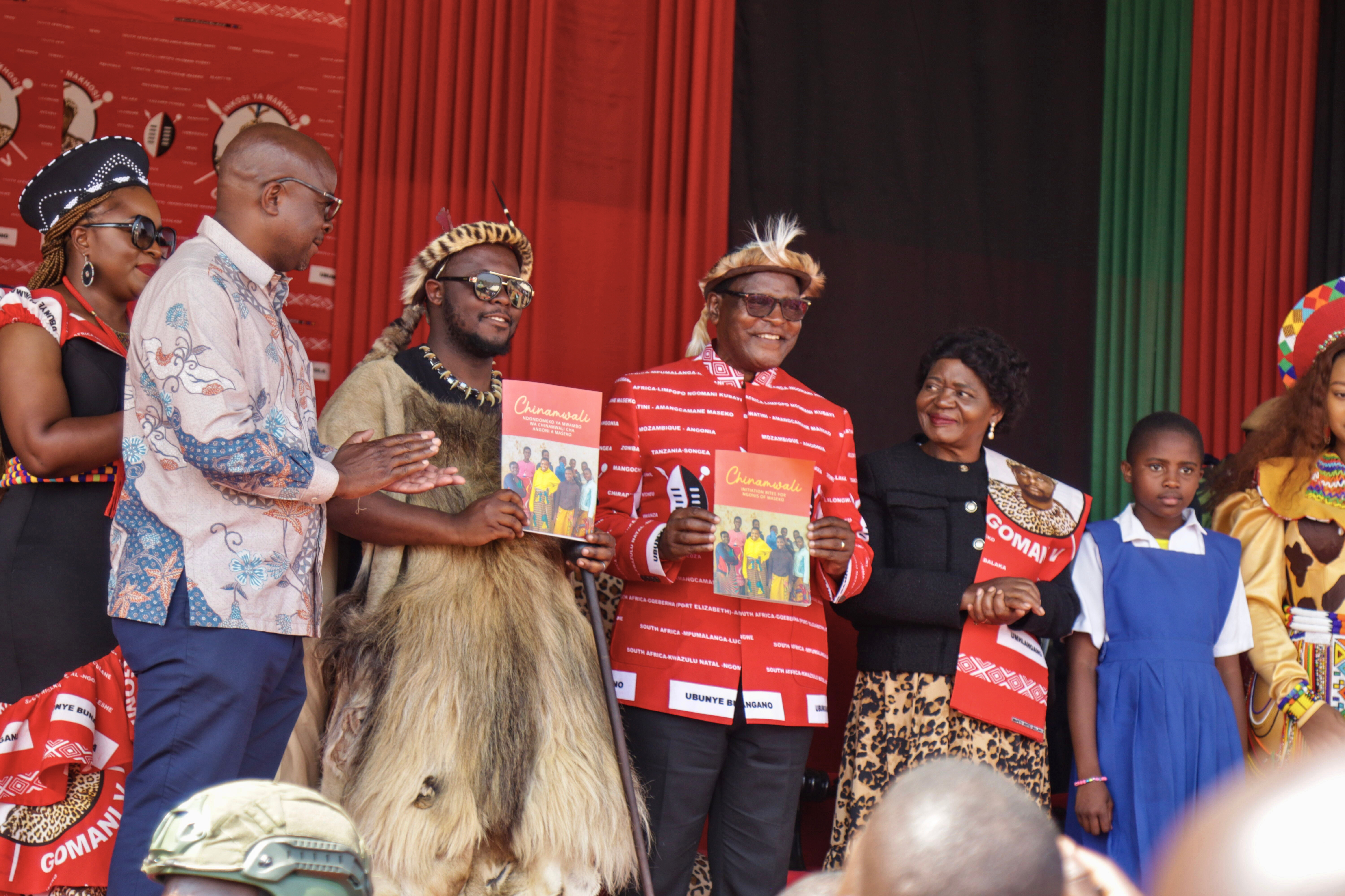 Inkosi Gomani showing the new guidebook, Malawi President, Dr Lazarus Chakwera wearing a  red shirt smiling as he shows the book.