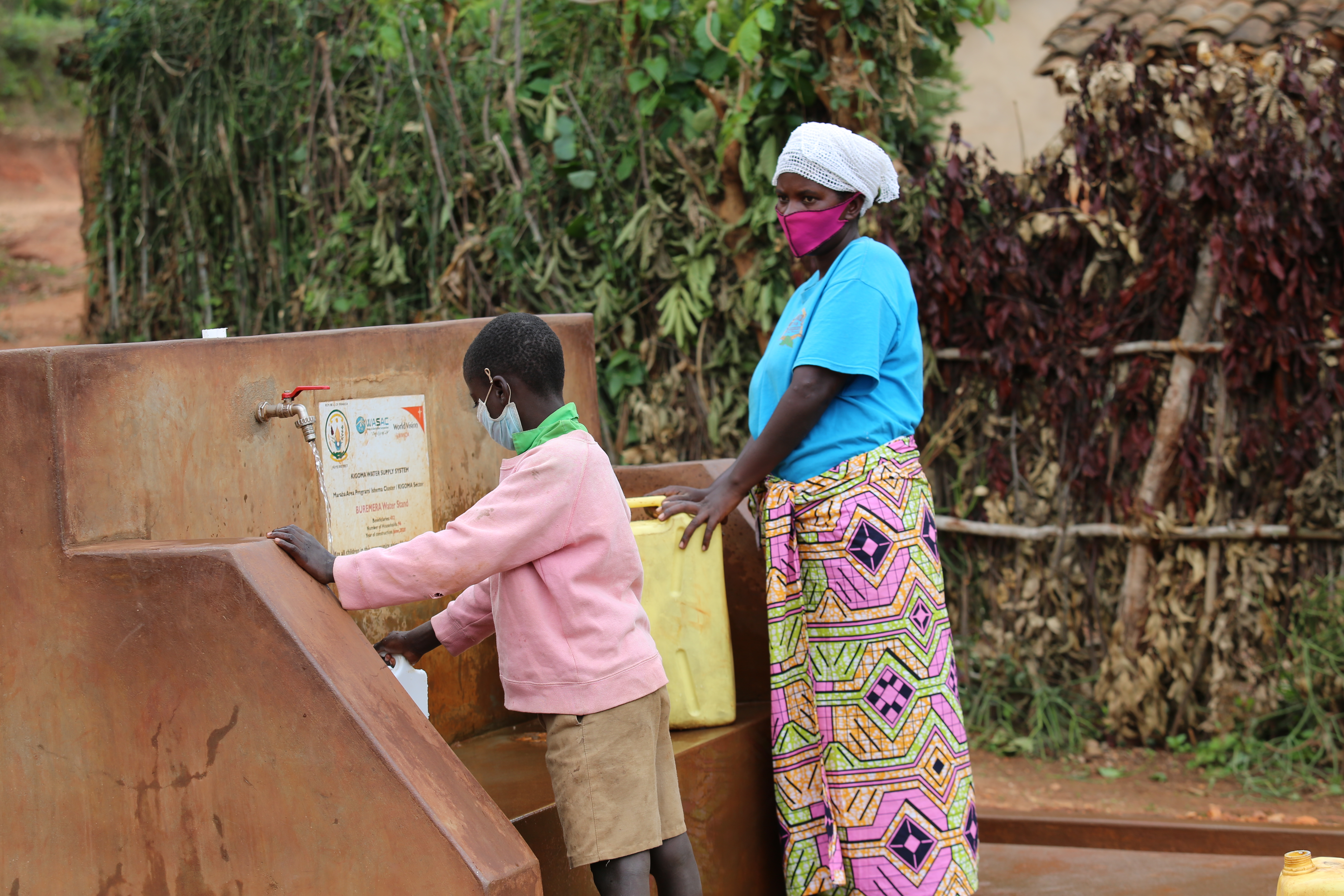 Elizabeth and her son Emmanuel fetching water at a nearby Water facility provided by World Vision