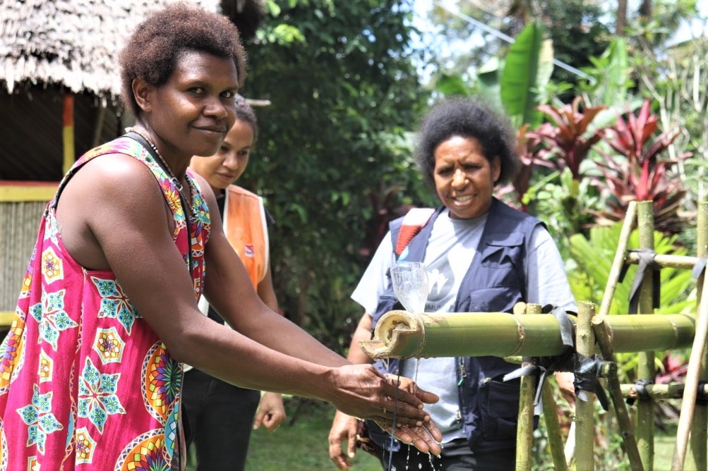 Angela Masit demonstrating how to   use a bamboo tippy tap in her plastic compound of Nawaeb District. Angela is behind the mobilisation of her community in reaching ODF status.