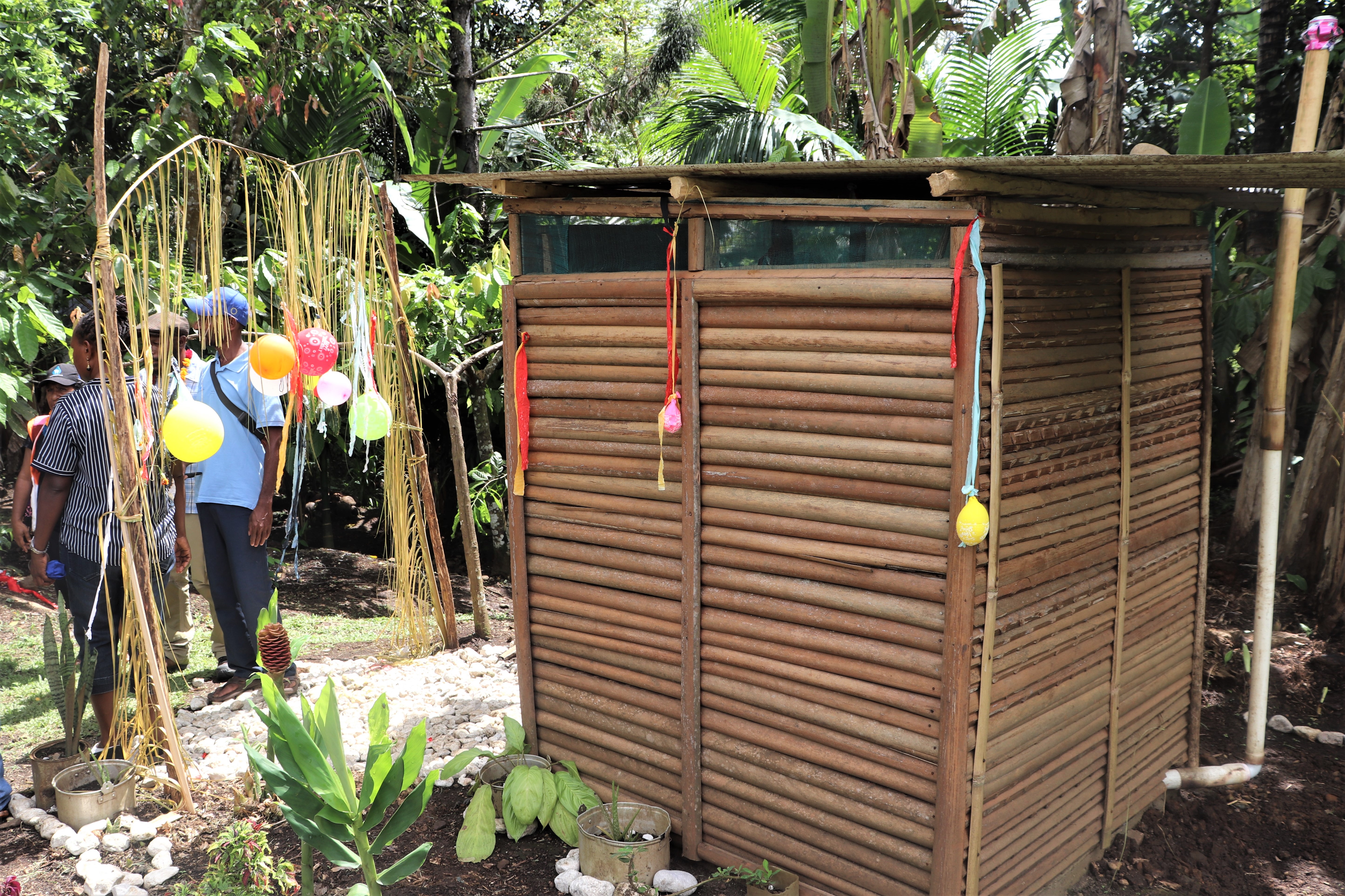 A family toilet with squat on sato pan inside, concrete slab floor and vent pipe and tippy tap.