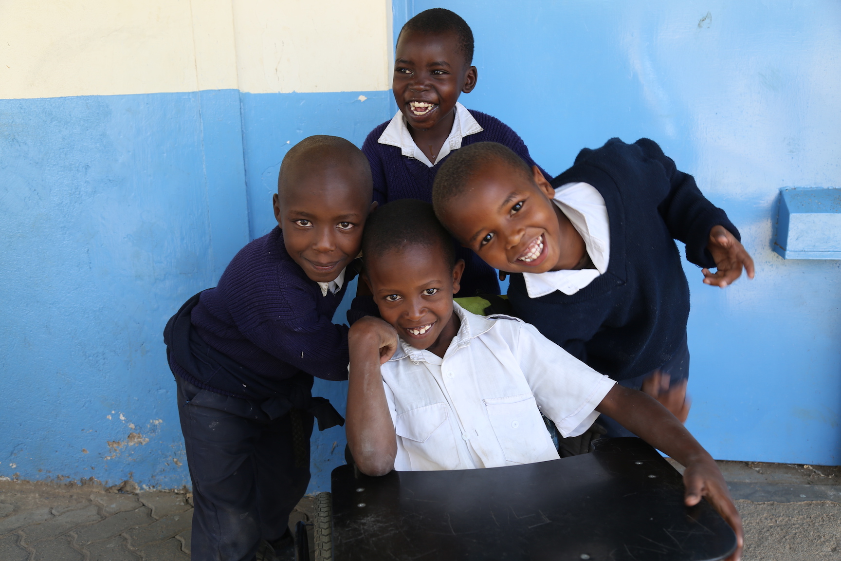 Gift, seated on his wheel chair surrounded by friends. The chair allows him to move around and play with fellow pupils. ©World Vision Photo/By Hellen Owuor.